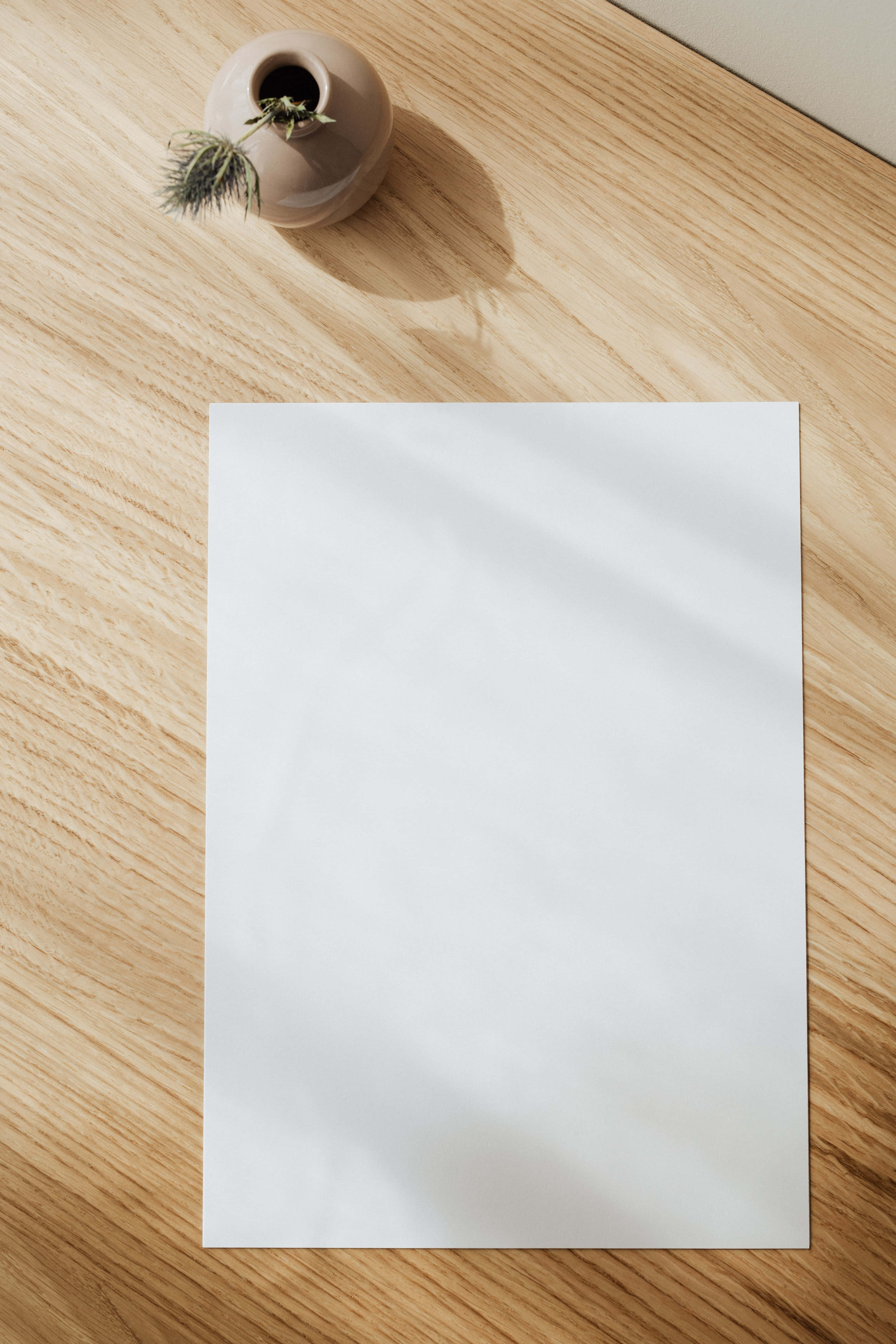 Sheet 桌布 壁紙 — 一張空白嘅白紙放喺淺色木面上，旁邊有一個細小嘅米色花瓶，插住一株乾燥植物。