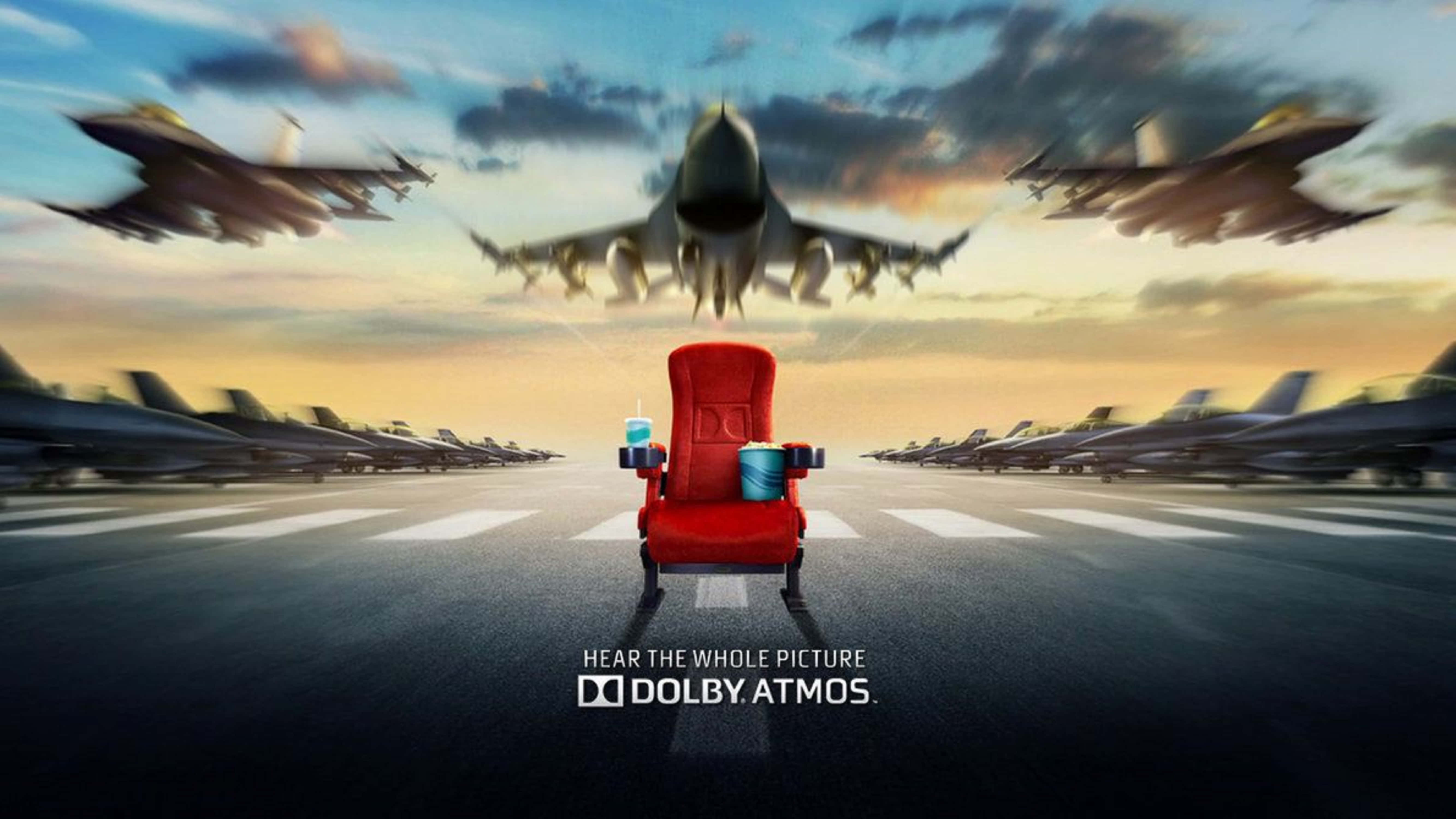 4K Dolby Vision 桌布 壁紙 — 一張紅色戲院座椅放在機場停機坪中央，戰鬥機在金色夕陽天空下呼嘯而過。