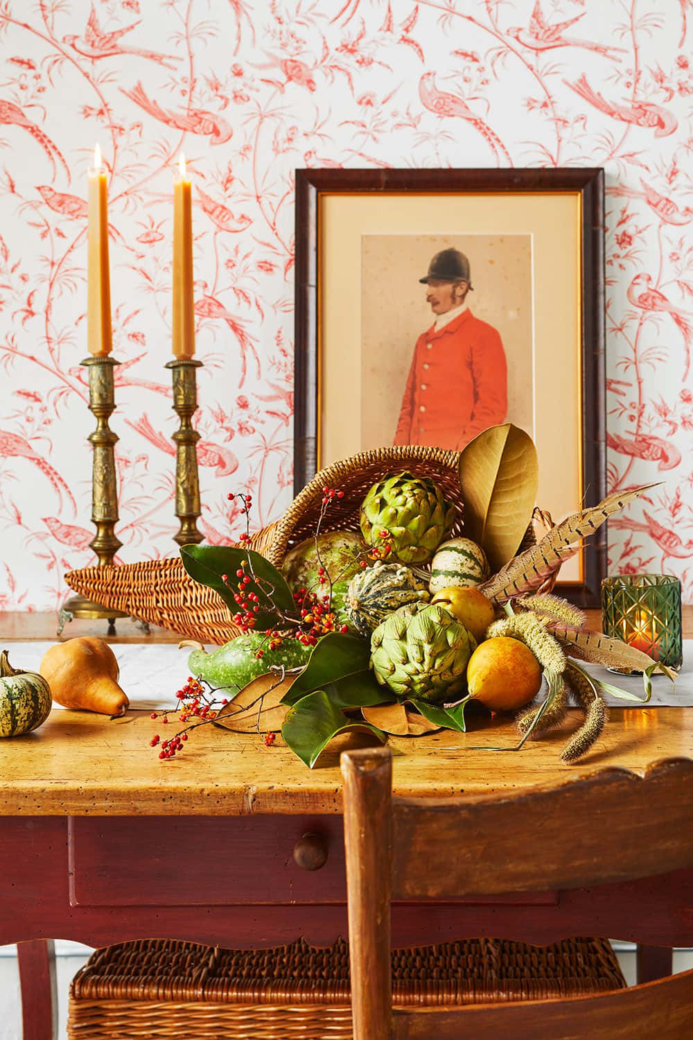 Fall Cornucopia 桌布 壁紙 — 一張質樸的木桌上展示著充滿活力的秋日靜物，有朝鮮薊、梨子和漿果，背景是紅色鳥圖案牆紙。