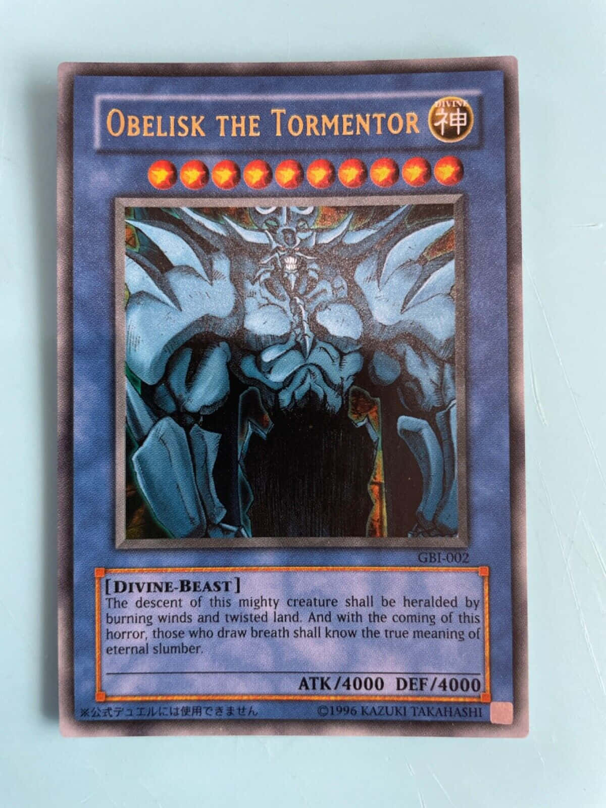 Obelisk The Tormentor 桌布 壁紙 — 一張遊戲王集換式卡牌，描繪了歐貝利斯克的巨神兵，帶有發光的紅色星星和深藍色翅膀，背景為紫色。