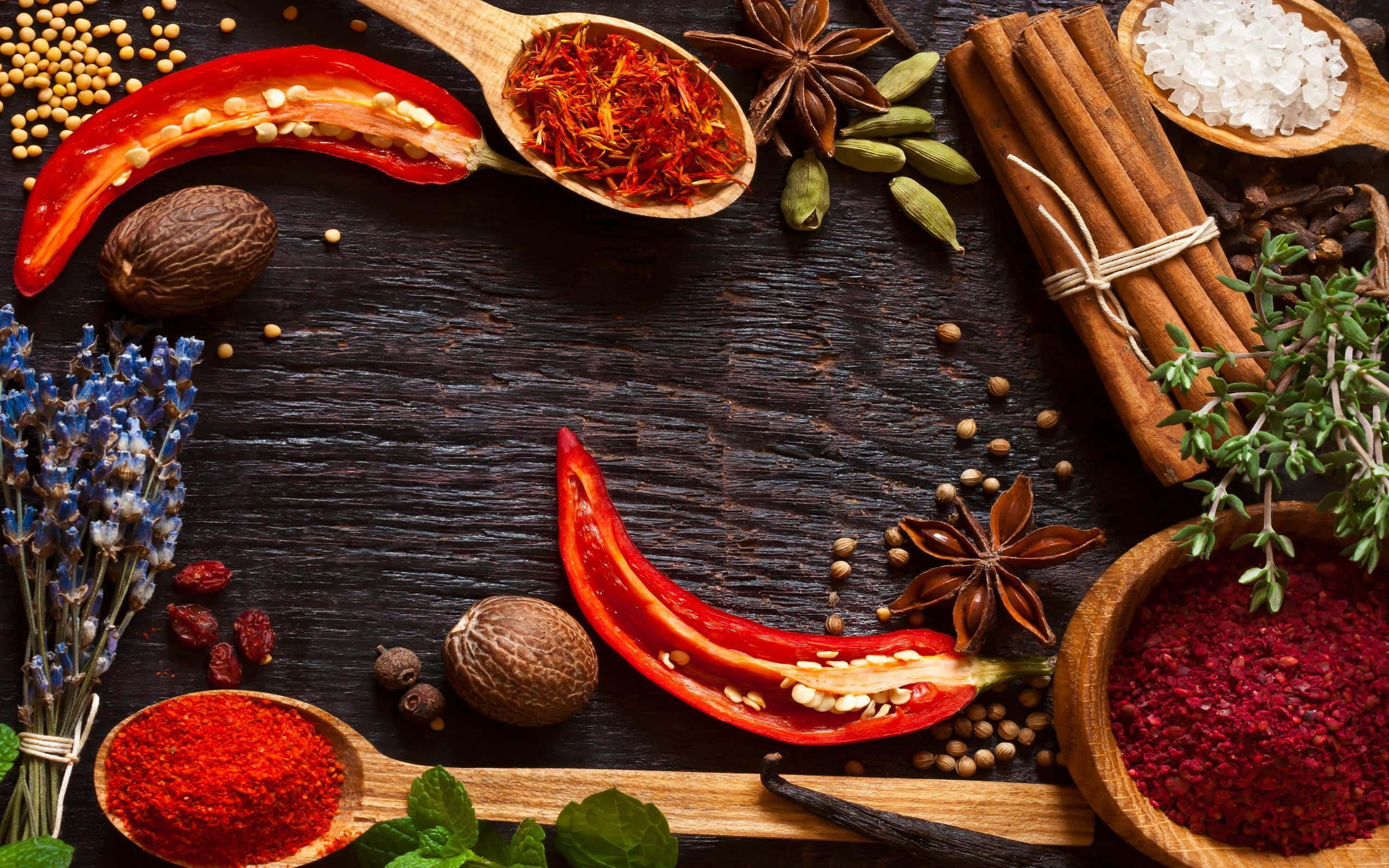 Spices 桌布 壁紙 — 一張鄉村風格的木桌上擺放著色彩鮮豔的香料和香草，如紅辣椒、藏紅花、肉桂和八角，放在木勺和木碗中。