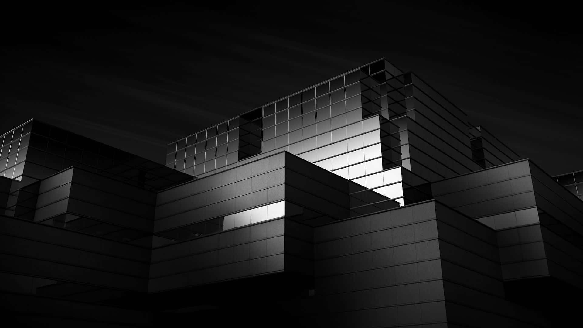 Black And White Architecture 桌布 壁紙 — 一張鮮明的黑白建築照片，拍攝夜晚的現代建築，發光的窗戶穿透深邃的陰影。