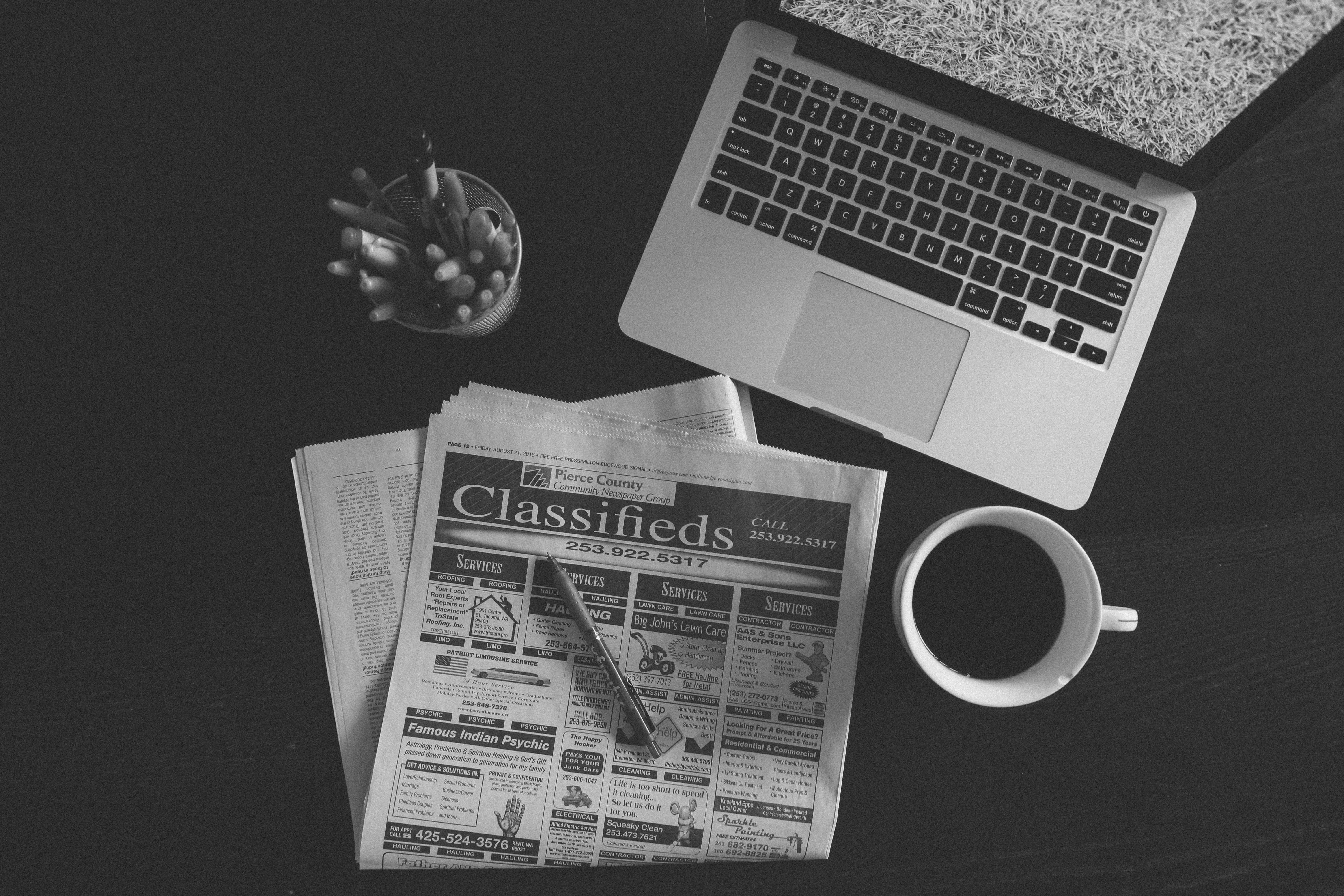 Newspaper 桌布 壁紙 — 一張黑白俯拍照片，顯示手提電腦、報紙、鉛筆和咖啡杯排列在深色桌子上。