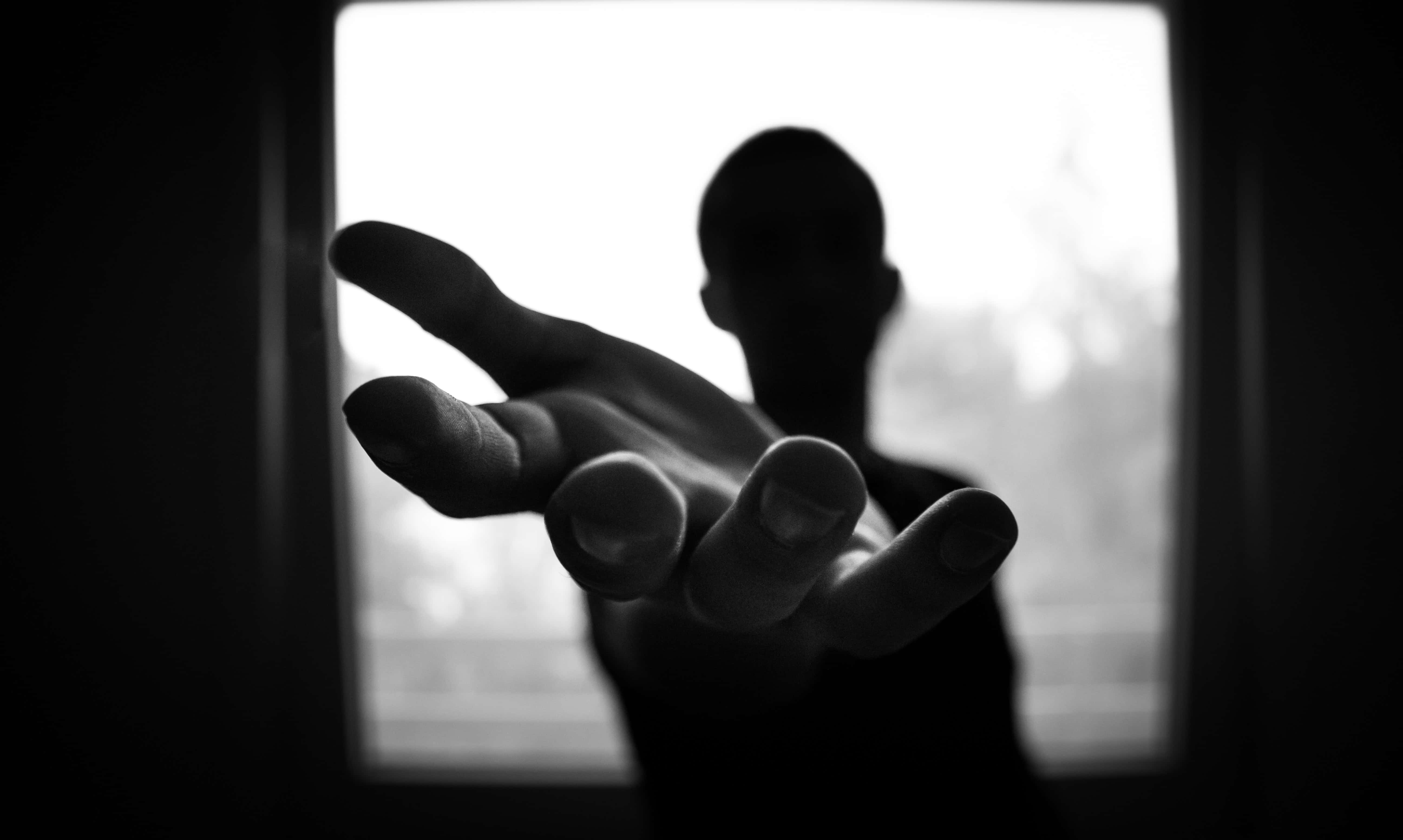 黑白美學 桌布 壁紙 — 一張黑白照片，一隻手向前伸出，背後有一個模糊的人影形成剪影。