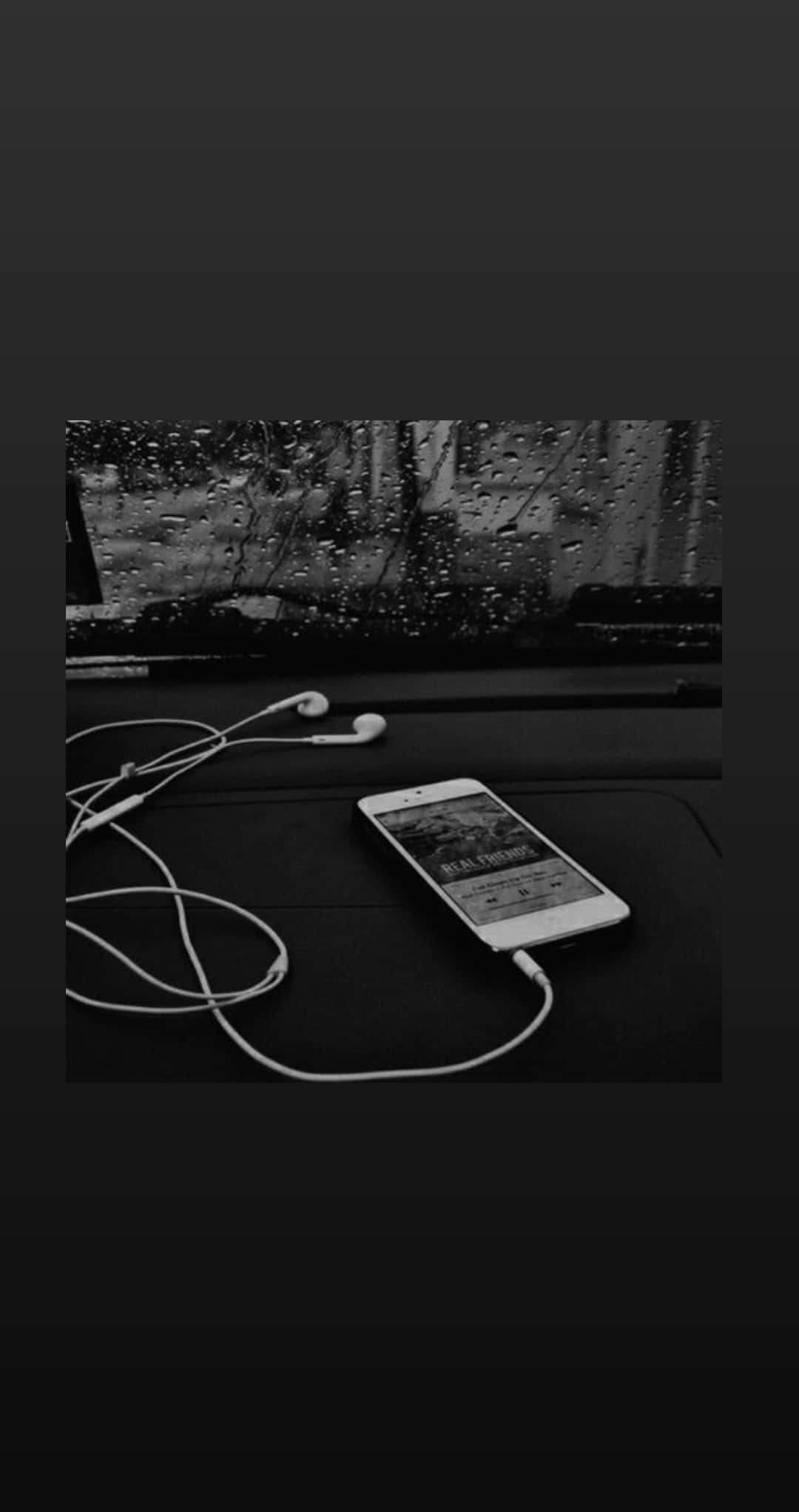Aesthetic Music 桌布 壁紙 — 一張黑白照片，顯示智能手機和耳機放在汽車儀表板上，後方車窗有雨滴流過。
