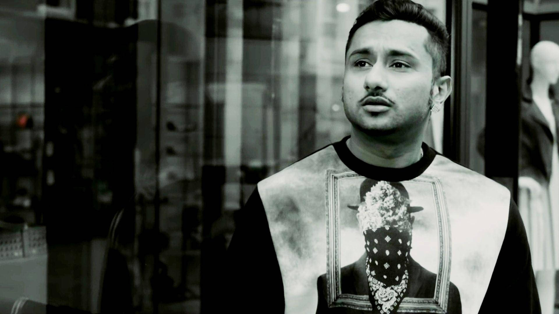 Yo Yo Honey Singh Kalley Rehende 壁紙 — 一張黑白照片中，一名男子站在玻璃店面櫥窗前，身穿印有戴面具人物裱框肖像的襯衫。