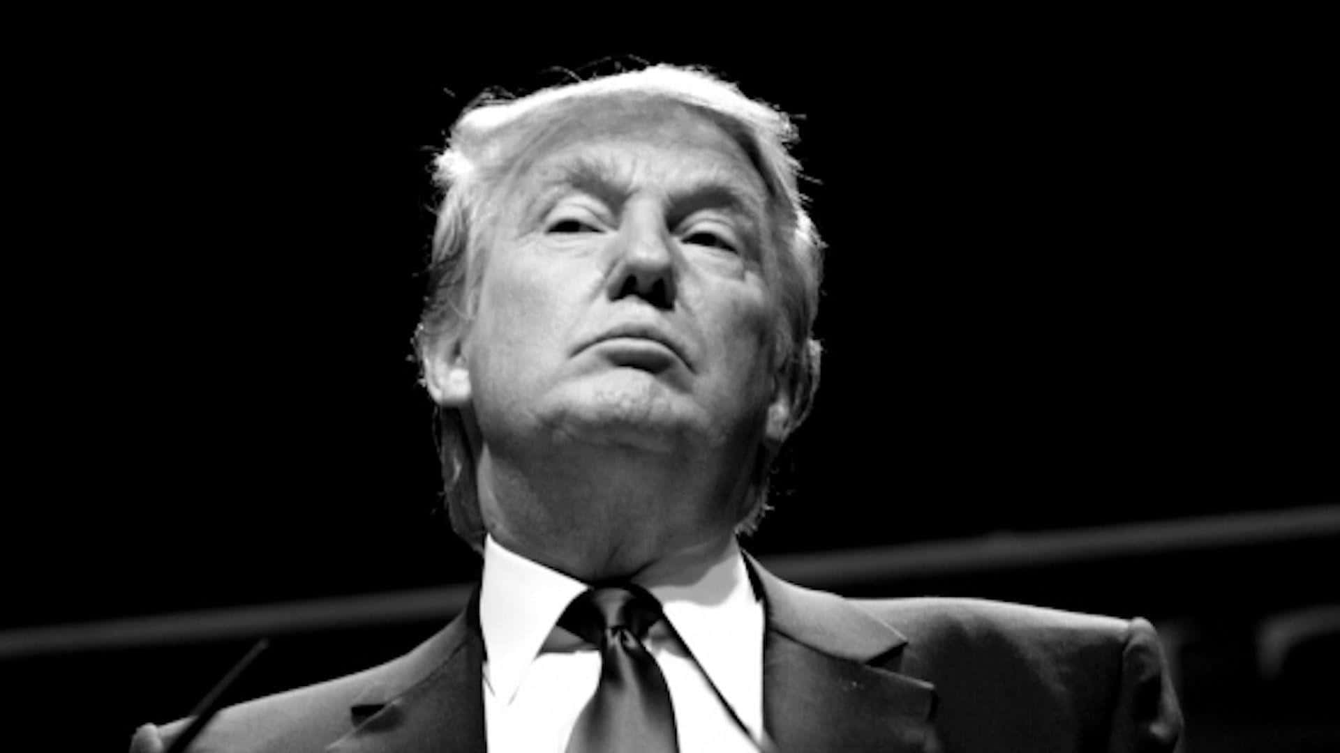 trump 桌布 壁紙 — 一張黑白特寫，唐納德·特朗普在深色背景下向上看，表情嚴肅。