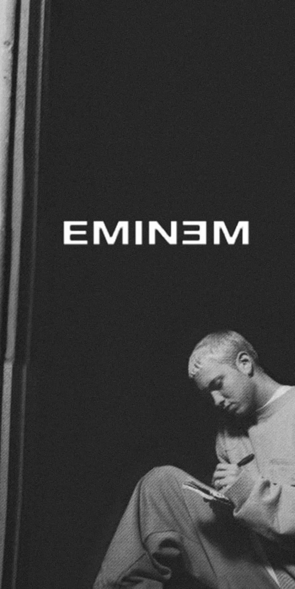 Eminem 桌布 壁紙 — 一張黑白肖像，Eminem 沉思地坐著，在黑暗背景下寫筆記本。
