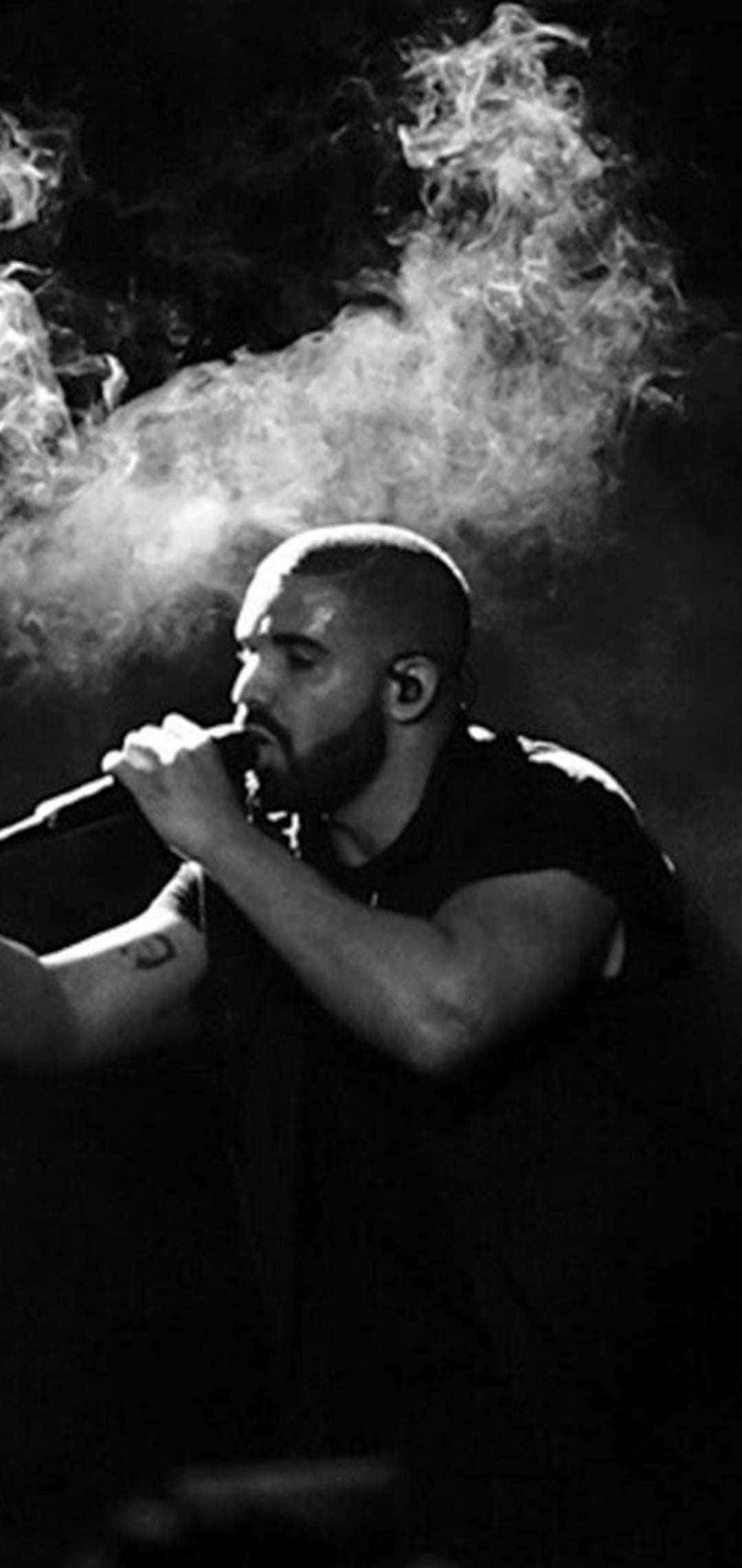 Drake 桌布 壁紙 — 一張黑白肖像，一名留鬍鬚的男子對著麥克風唱歌，煙霧在他周圍戲劇性地旋轉。