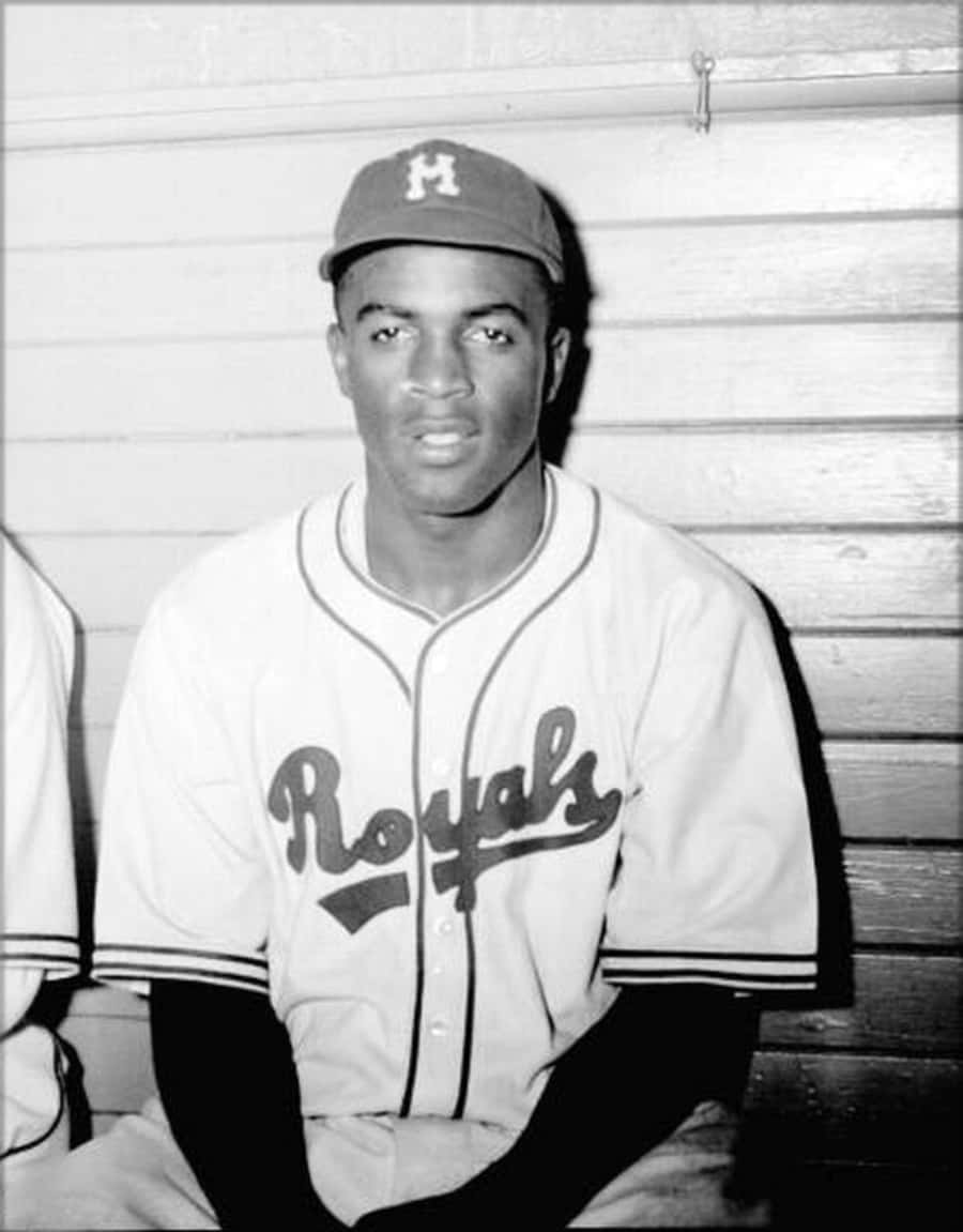 Jackie Robinson 桌布 壁紙 — 一張黑白肖像，一名身穿皇家隊球衣的棒球運動員坐在木凳上，表情嚴肅。