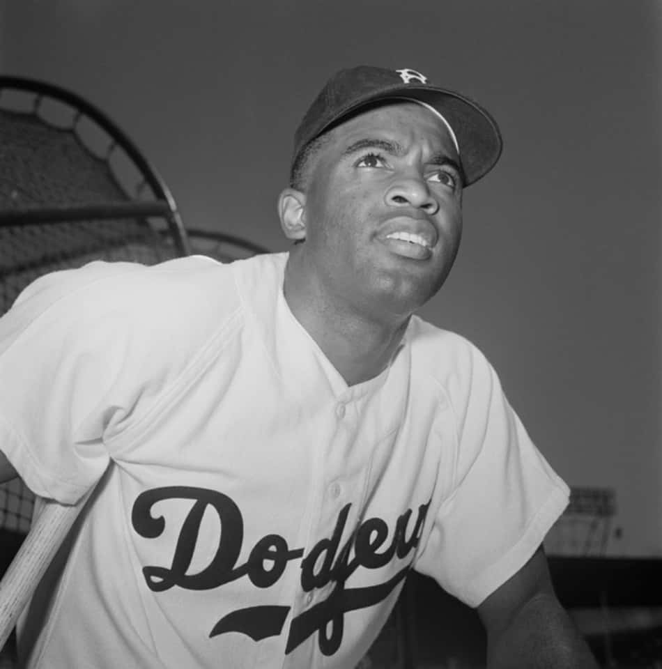 Jackie Robinson 桌布 壁紙 — 一張黑白肖像，一名身穿道奇隊球衣的棒球運動員仰望上方，球棒放在身旁。