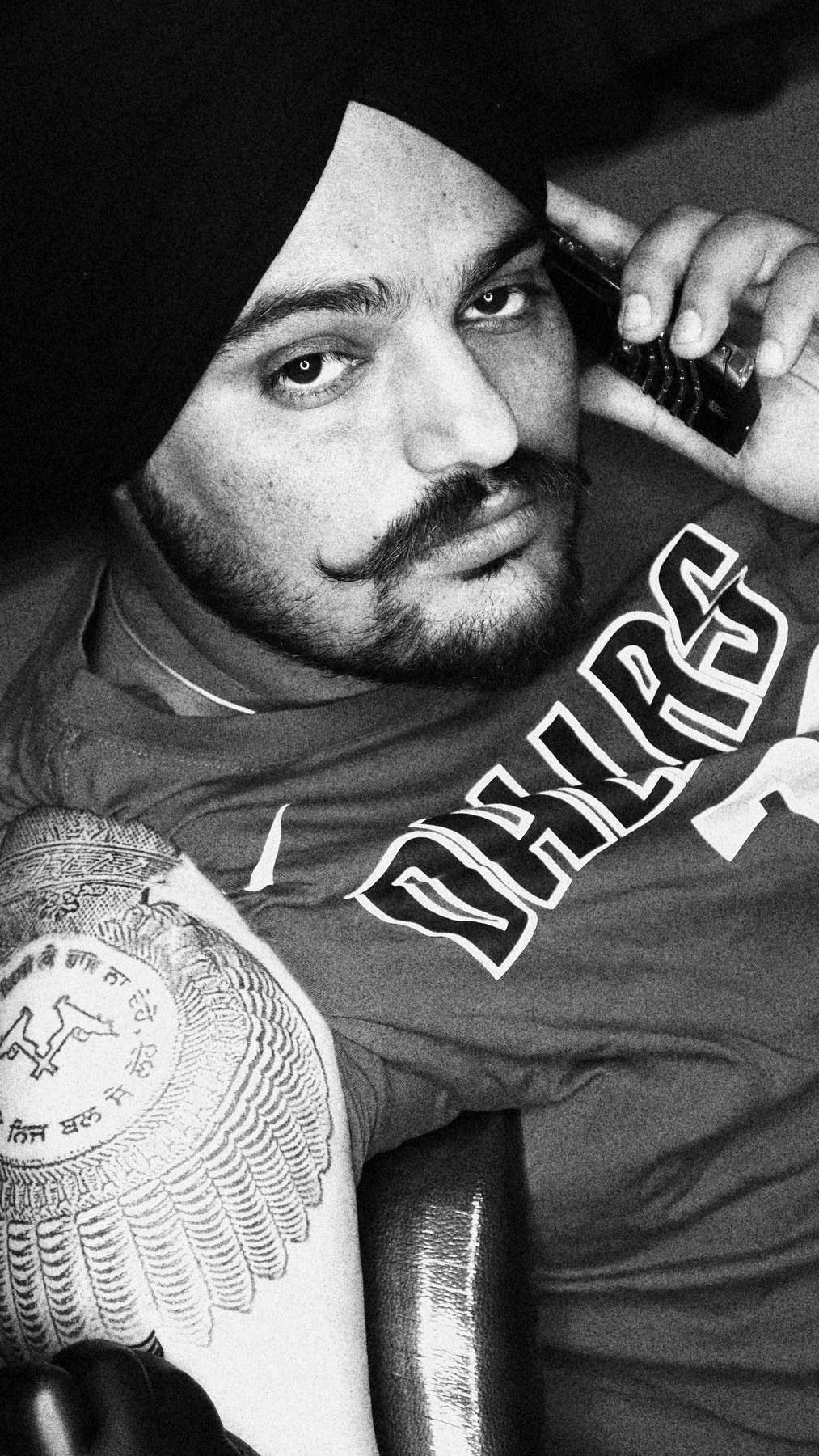 Indian 桌布 壁紙 — 一張黑白肖像照，一名戴頭巾的男子將電話貼在耳邊，可見其有紋身的手臂。