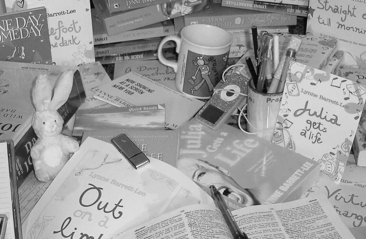 Journalism 桌布 壁紙 — 一張黑白雜亂的書桌，堆滿了書籍、筆記本、一個毛絨兔子和書寫工具，營造出一個舒適的創意工作空間。