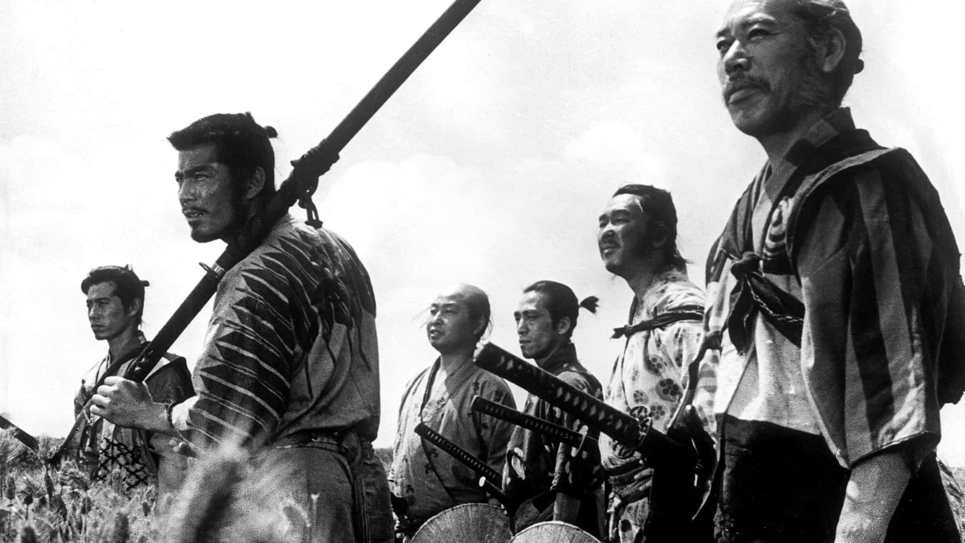 Akira Kurosawa 桌布 壁紙 — 一張黑白電影劇照顯示六名身穿傳統服飾的武士站在田野中，手持步槍和刀劍。