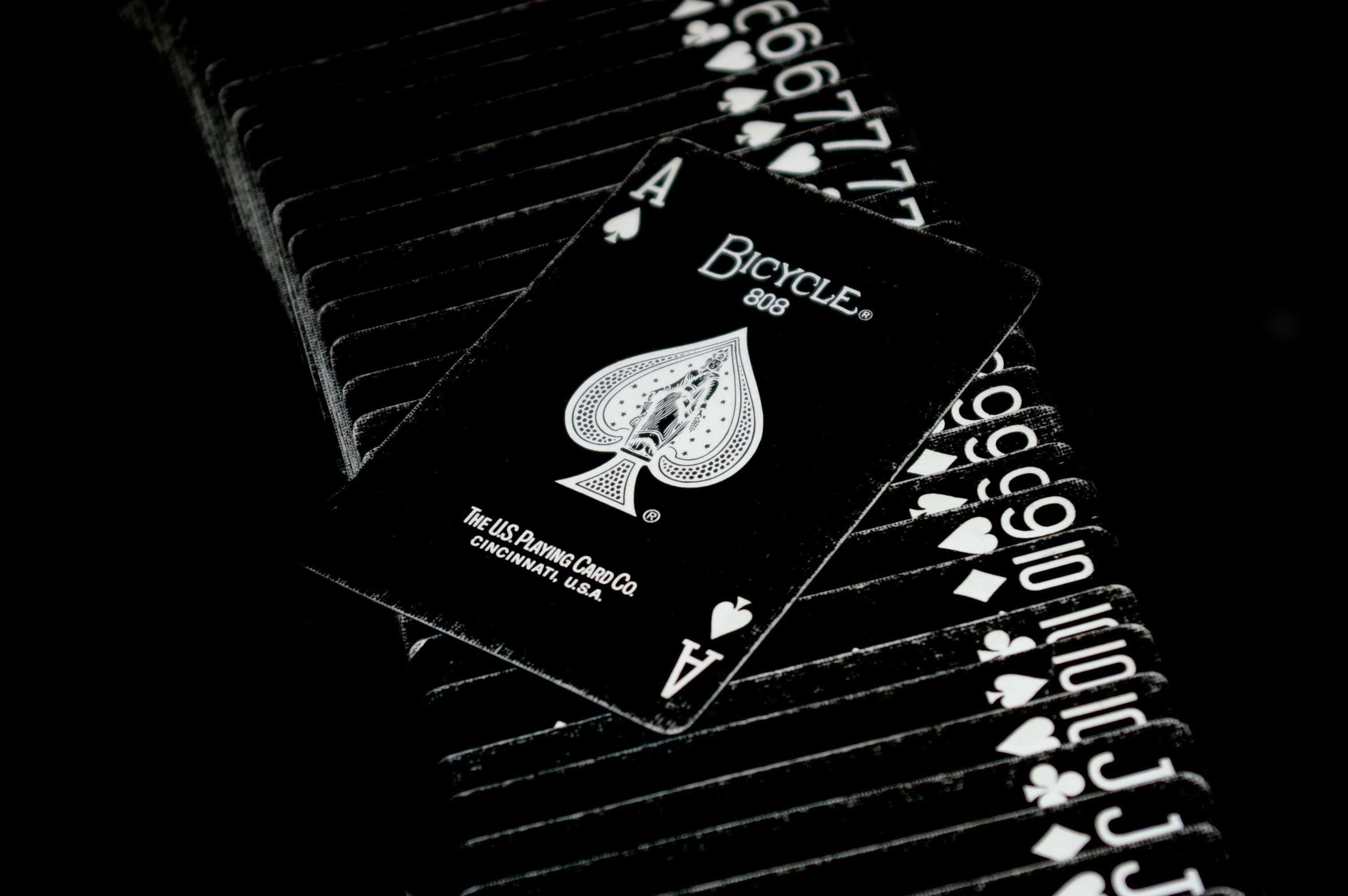 Card Games 桌布 壁紙 — 一張黑色Bicycle黑桃Ace牌放在深色背景前扇形展開的啤牌堆上。