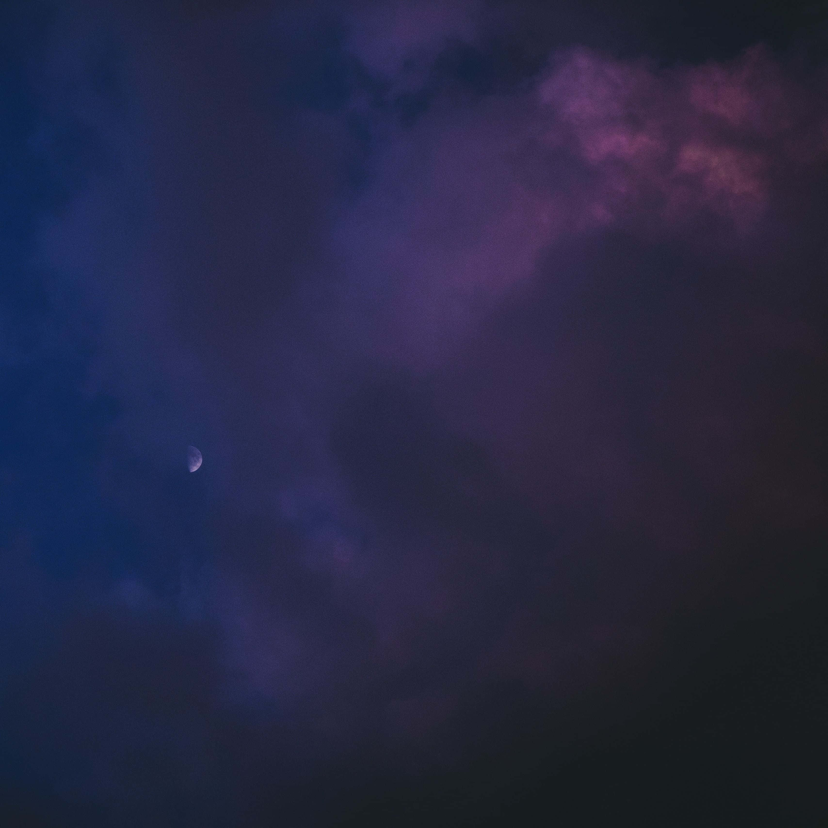 Dark Sky 桌布 壁紙 — 一彎新月在深紫色和藍色繪成的戲劇性暮色天空中，伴著縷縷薄雲柔和地發光。