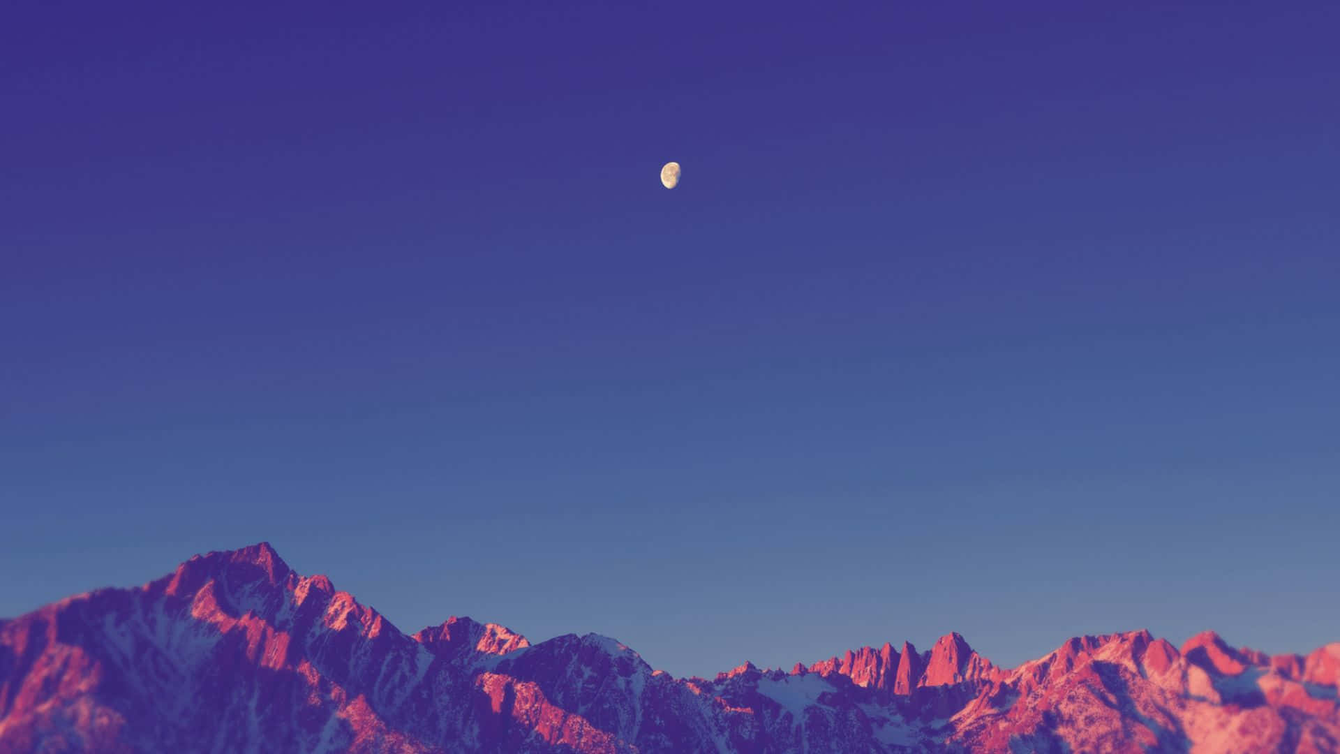 Minimalist Sunset 桌布 壁紙 — 一彎新月懸掛在鋸齒狀的雪山之上，沐浴在粉紅和紫色的暮色之中。