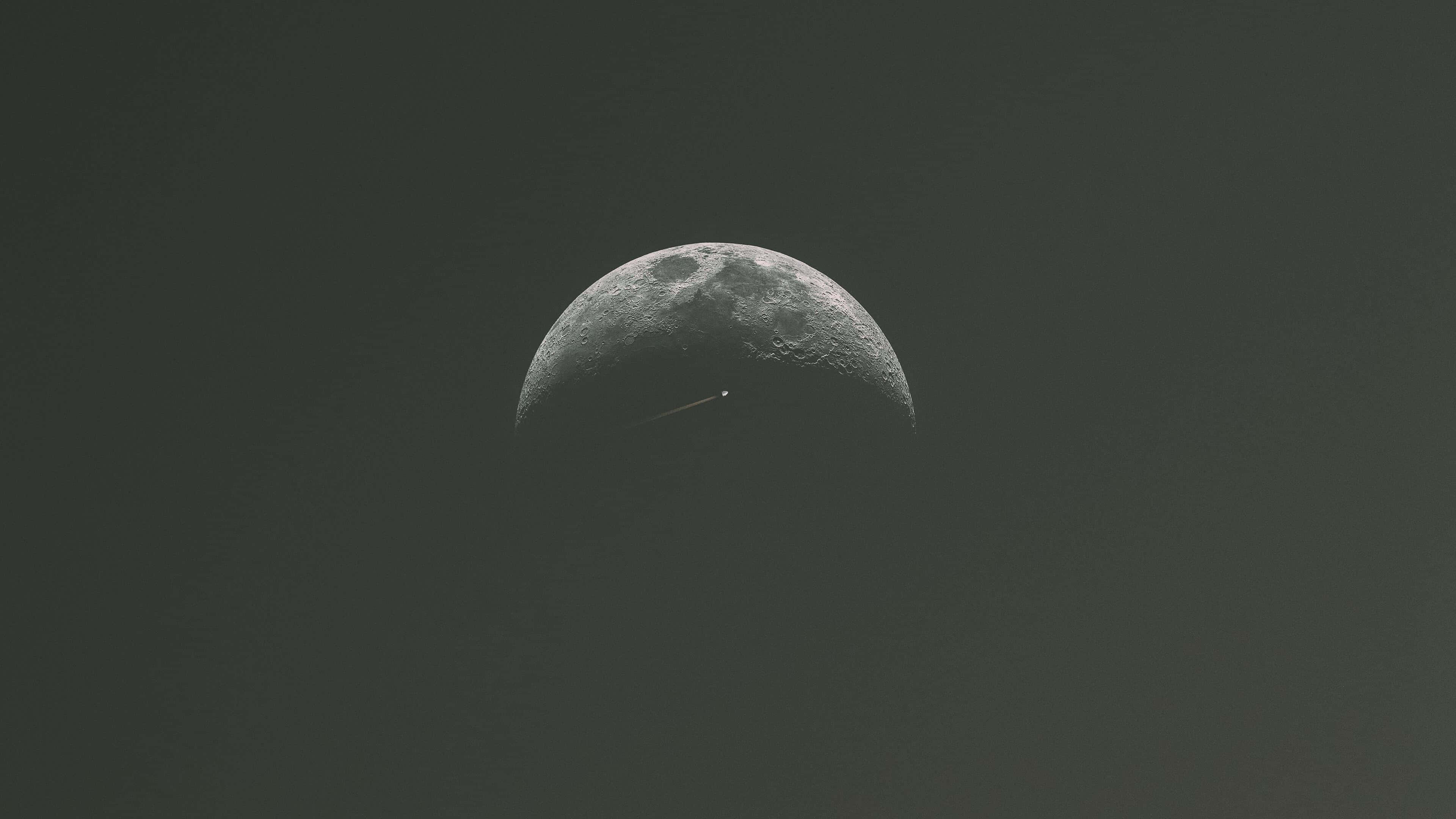Minimalist Space 桌布 壁紙 — 一彎新月表面有一條細小明亮的條紋，懸掛在昏暗的天空中。
