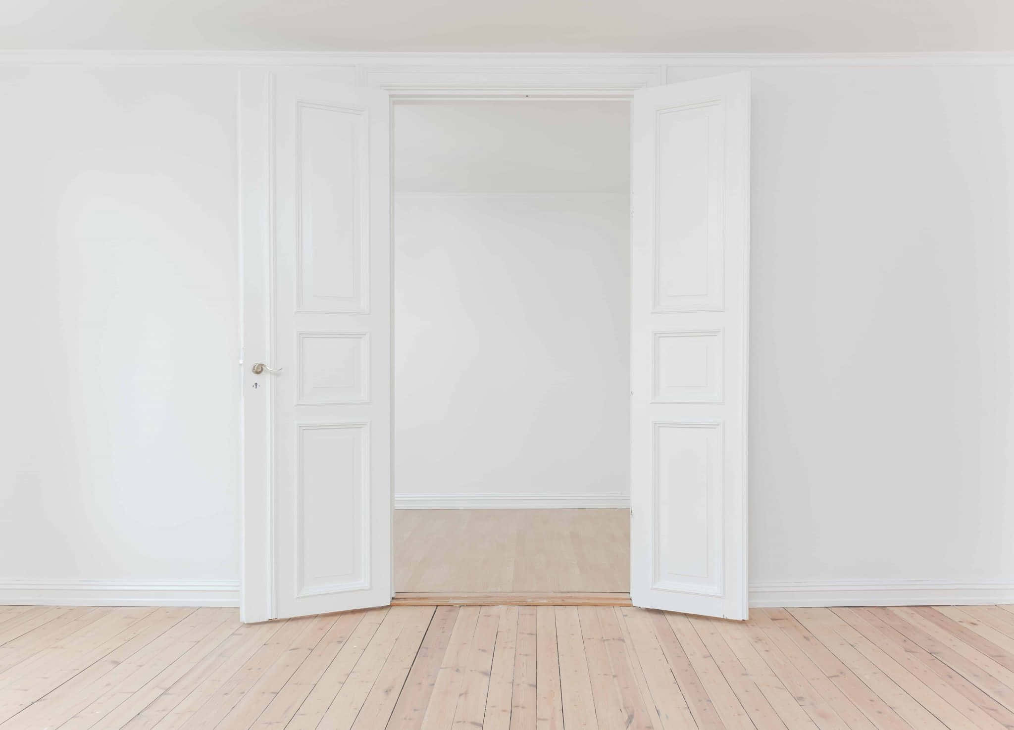 Door 桌布 壁紙 — 一扇簡約風格的白色雙門在明亮空曠的房間中敞開，地板為淺色木質。
