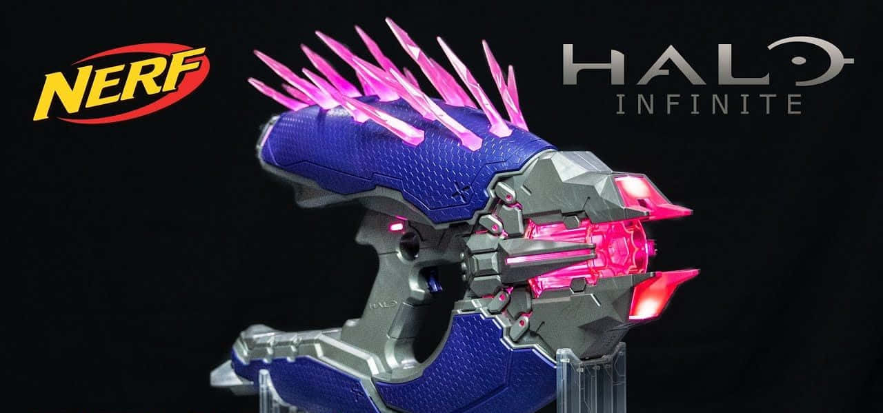 Halo Needler 桌布 壁紙 — 一把發光的粉紅色和藍色Nerf槍，風格仿照Halo Infinite的武器，在黑色背景上展示並帶有標誌。
