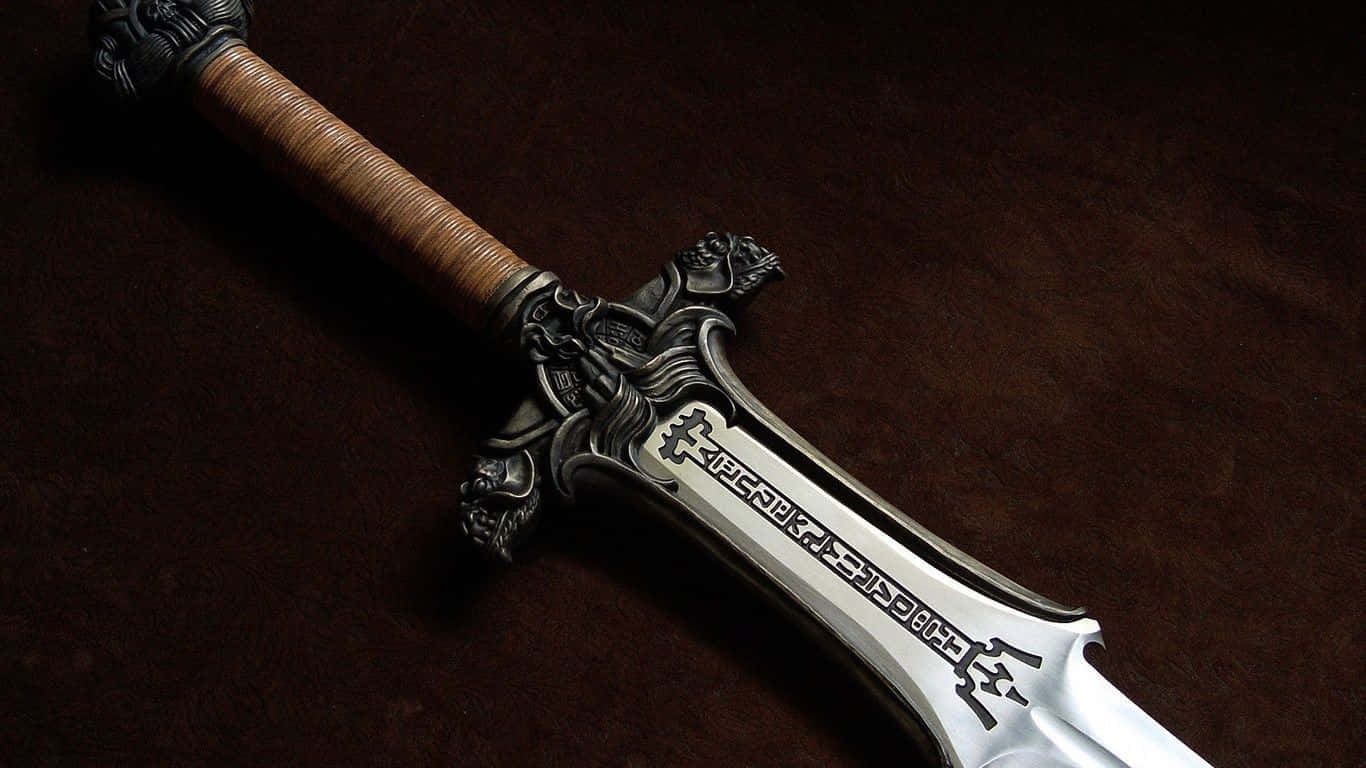 Ancient Weapons 桌布 壁紙 — 一把細節豐富的奇幻劍，飾有華麗的銀色劍柄和雕刻劍刃，對角放置在深棕色天鵝絨表面上。