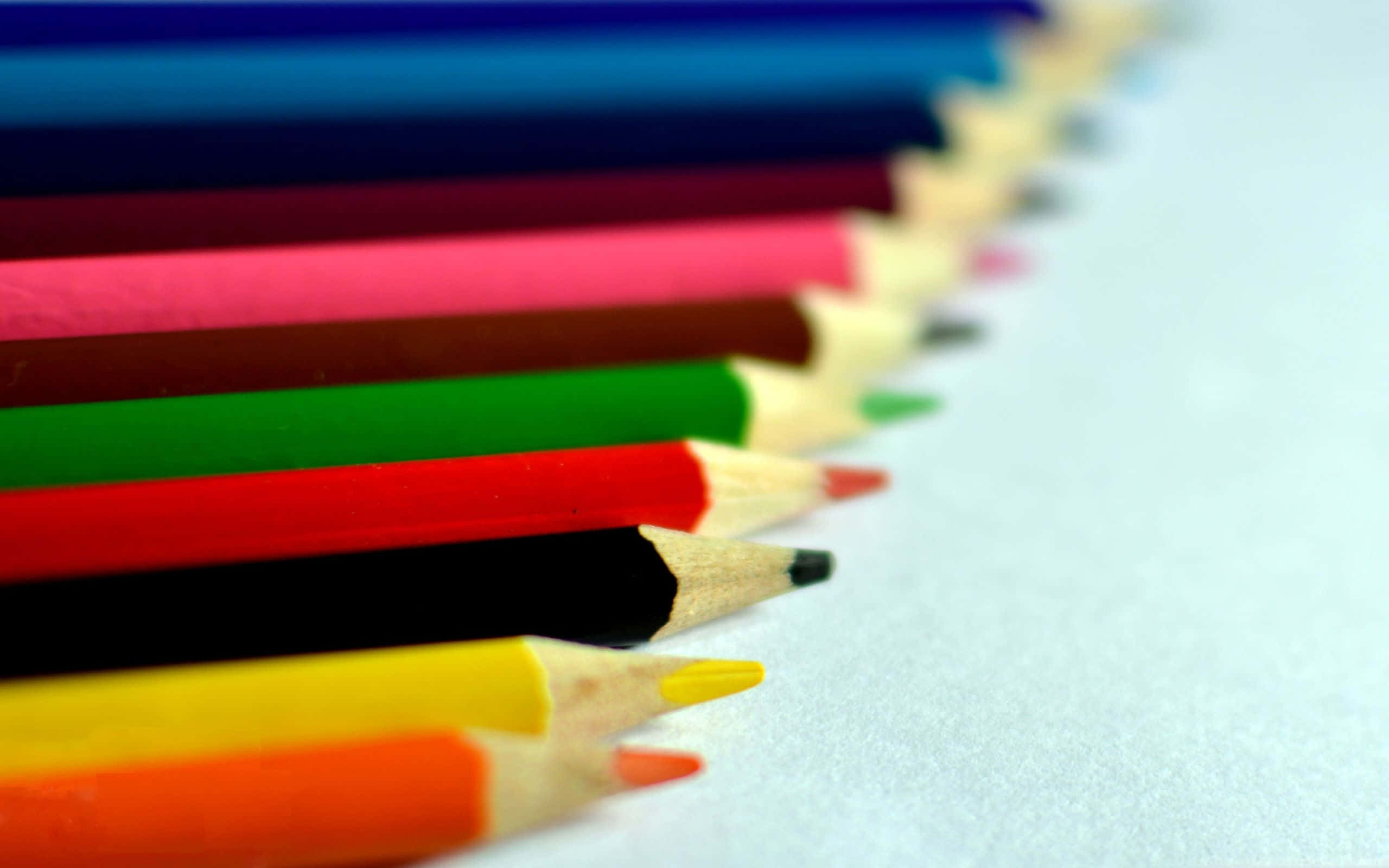 pencil 桌布 壁紙 — 一排削尖的彩色鉛筆以鮮豔色調對角排列，放置在柔軟的白色表面上，景深較淺。
