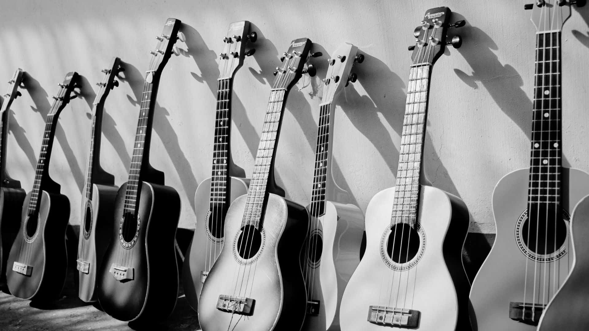 Black And White Guitar 桌布 壁紙 — 一排原聲結他靠牆而立，投射出長長的陰影，呈現高對比度的黑白效果。