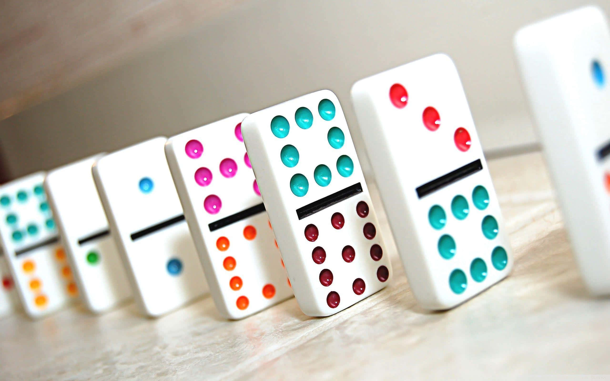 Domino 桌布 壁紙 — 一排帶有光澤圓點的彩色多米諾骨牌在淺景深中直立於淺色木質表面上。