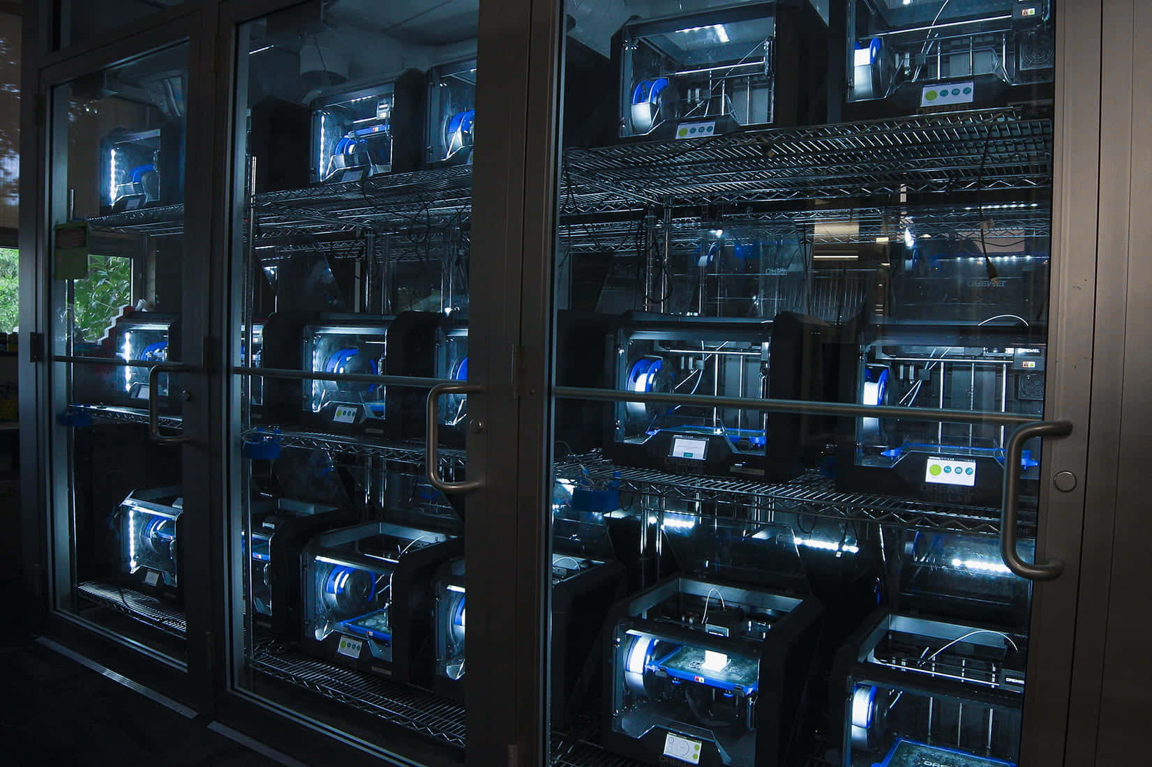3d Printer 桌布 壁紙 — 一排排3D打印機在昏暗房間的玻璃櫃內發出藍光。