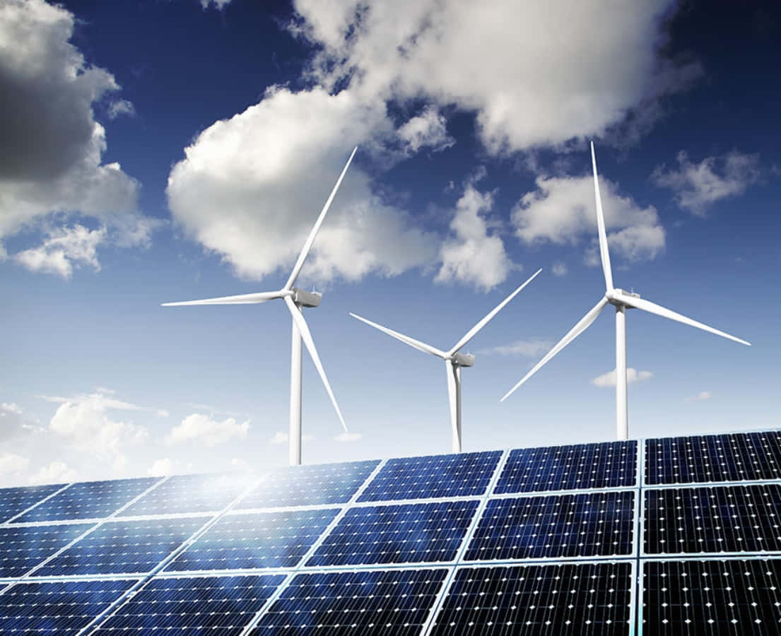 Energy 桌布 壁紙 — 一排排藍色太陽能板在明亮的藍天下延伸，天空點綴著蓬鬆的白雲，背後矗立著三座白色風力發電機。