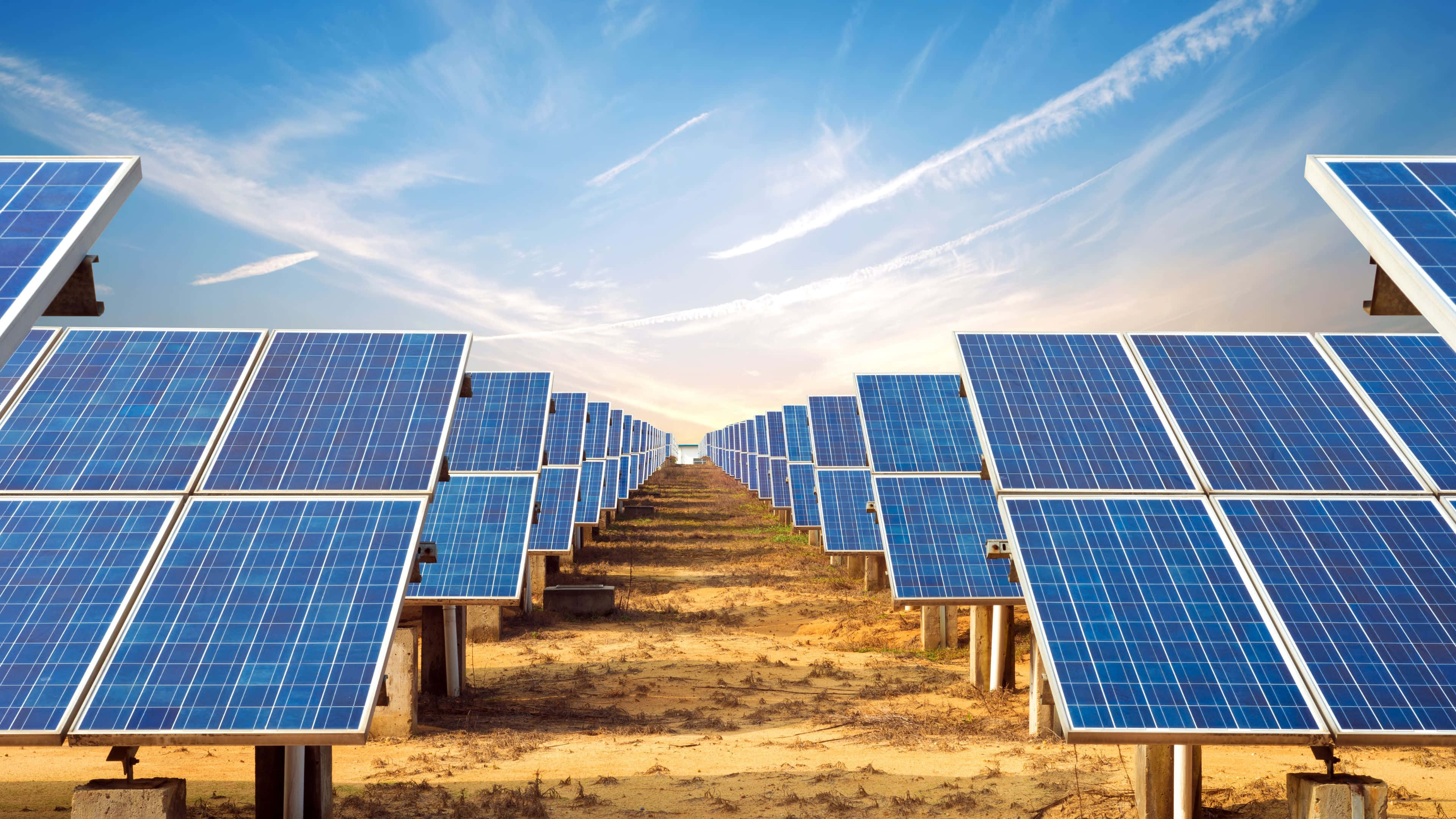Solar Panel 桌布 壁紙 — 一排排藍色太陽能板在晴朗藍天和薄雲下延伸至遠方。