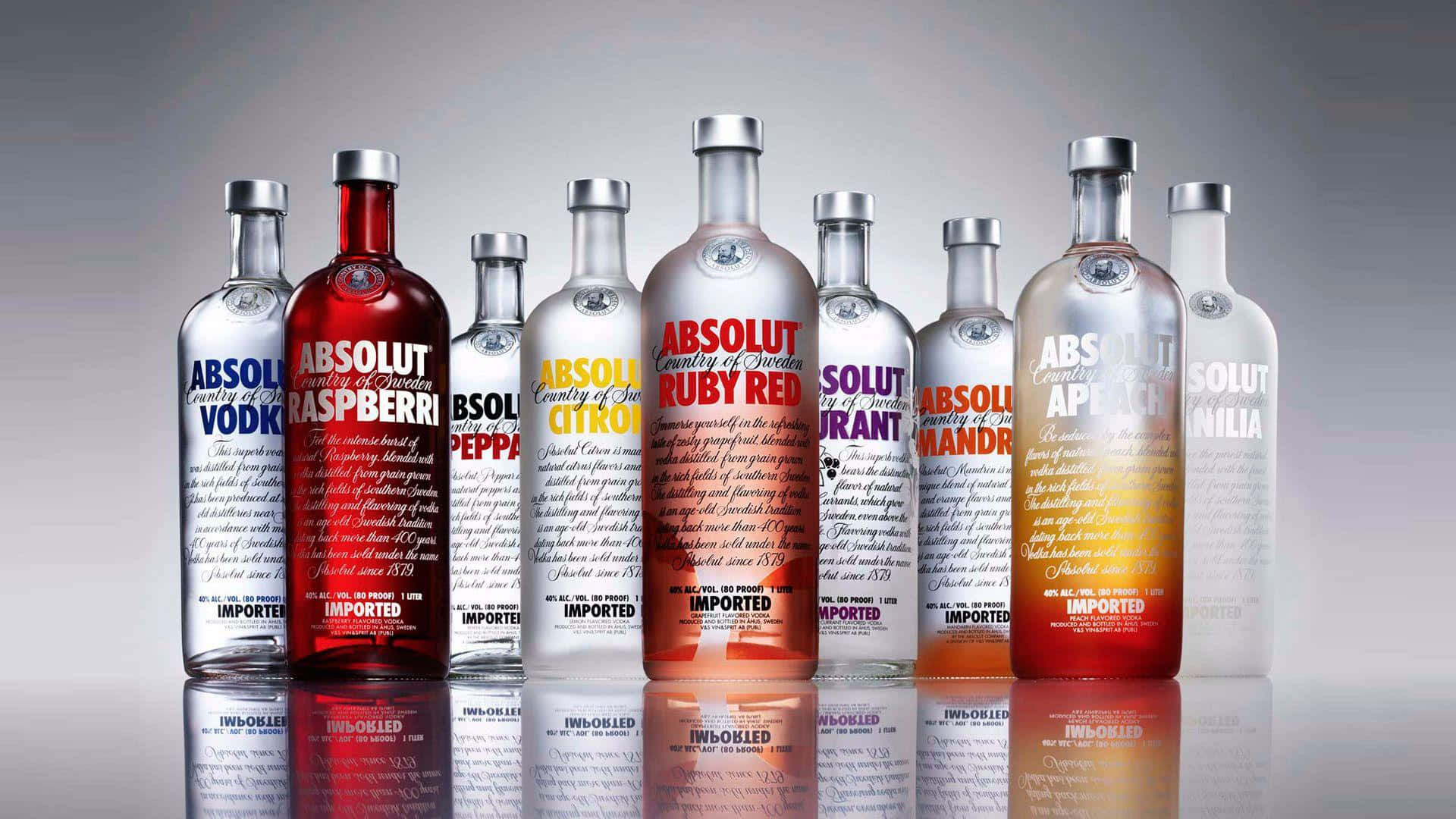 alcohol 桌布 壁紙 — 一排色彩繽紛、口味各異的Absolut伏特加酒瓶，放置在帶有反射表面的攝影棚環境中。