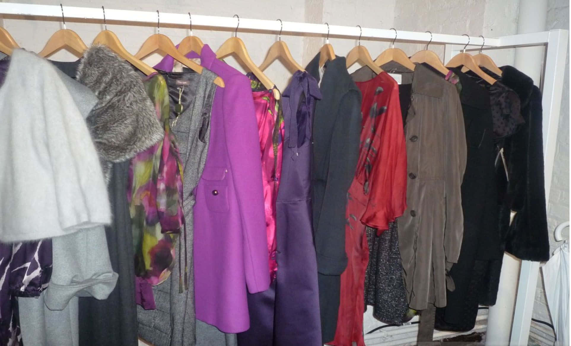 Winter Fashion 桌布 壁紙 — 一排色彩繽紛嘅外套同夾克整整齊齊咁掛喺木衣架上，靠住白色牆壁喺衣櫃入面。