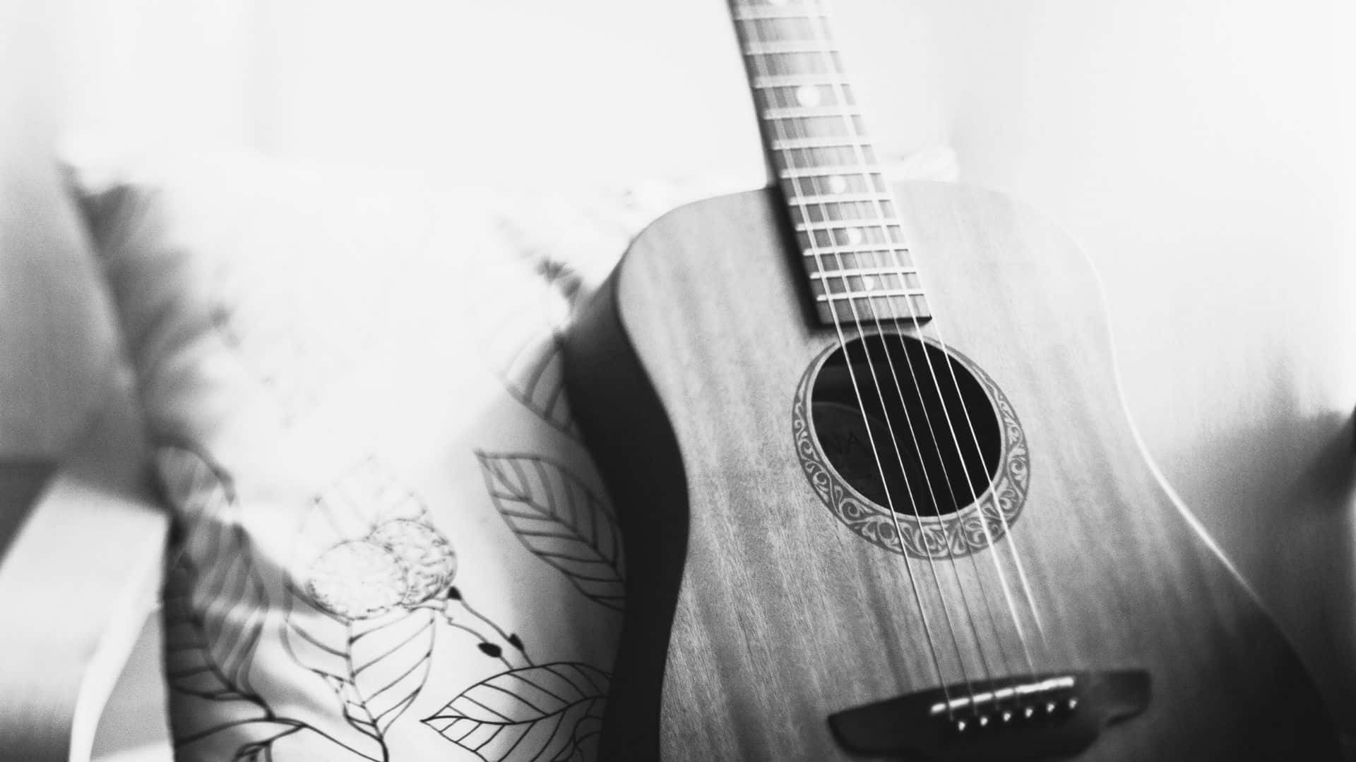 Black And White Guitar 桌布 壁紙 — 一支單色原聲結他靠在有圖案的枕頭上，光線柔和擴散。