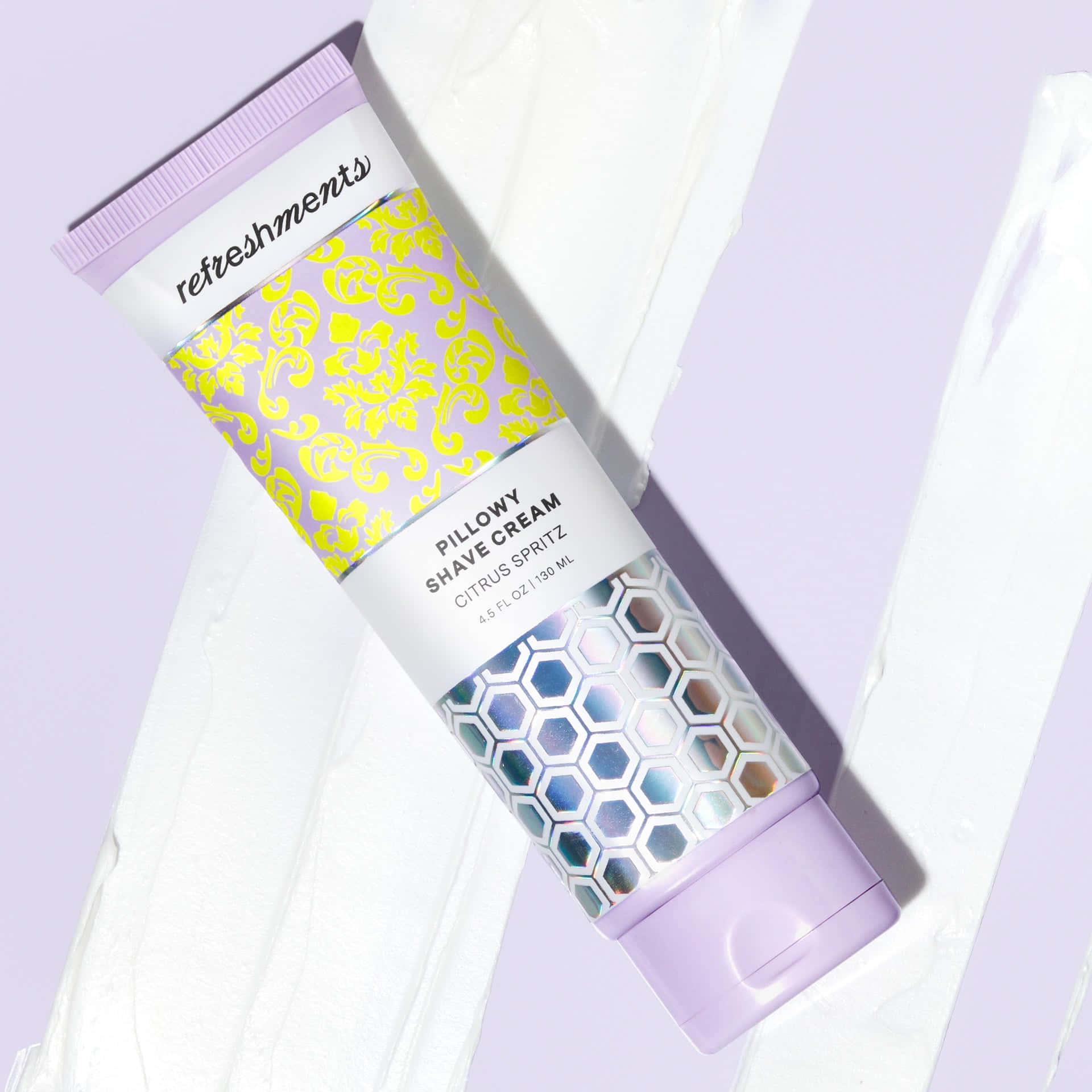 Shaving Cream 桌布 壁紙 — 一支帶有柑橘噴霧的Refreshments Pillowy Shave Cream剃鬚膏管斜放在薰衣草背景上，帶有白色奶油漩渦。
