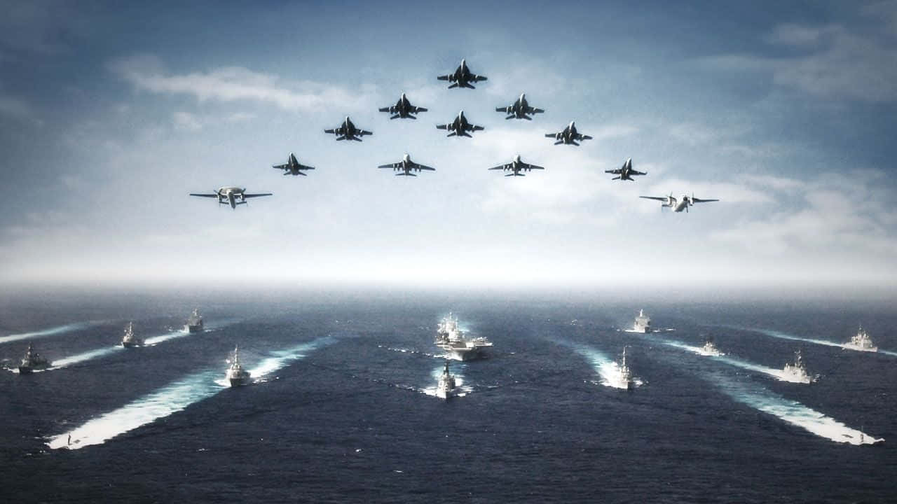 Navy 桌布 壁紙 — 一支戰艦艦隊在廣闊的海洋上編隊航行，戰鬥機以緊密的鑽石編隊在上空飛行。
