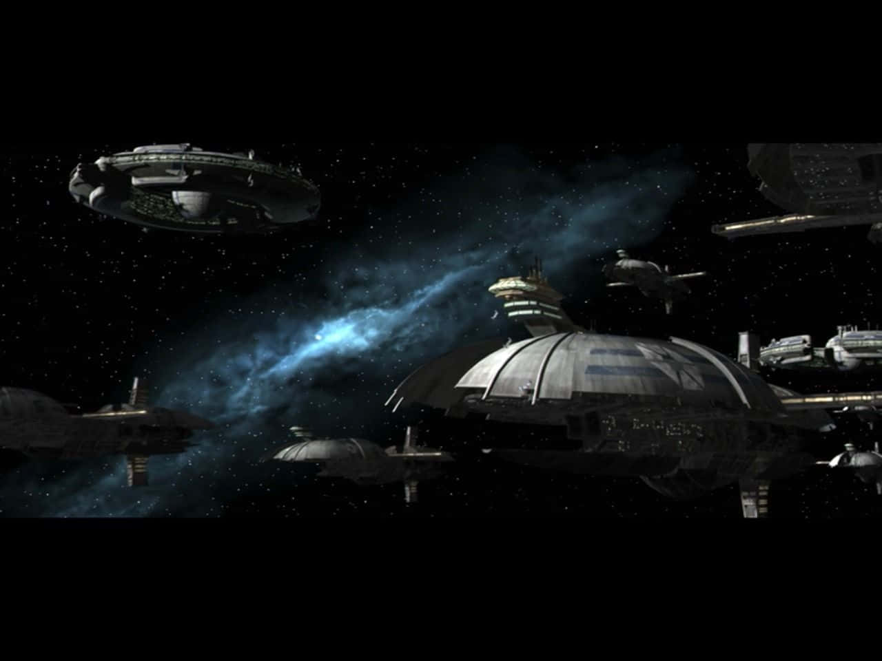 The Trade Federation 桌布 壁紙 — 一支未來風格的太空船艦隊在星空背景中航行，背景有發光的藍色星雲。