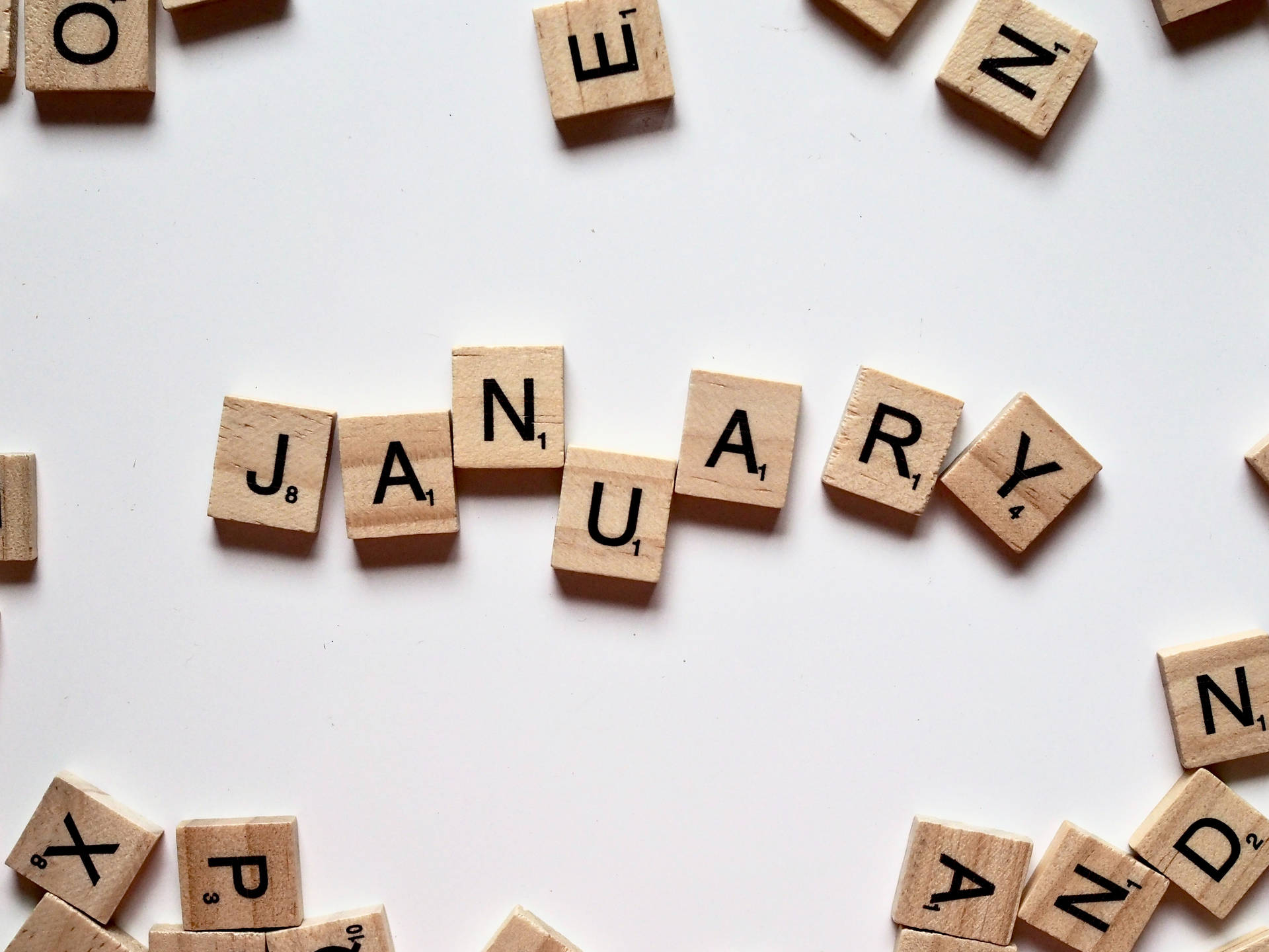木製 Scrabble 字母塊在白色表面上拼出「一月」。