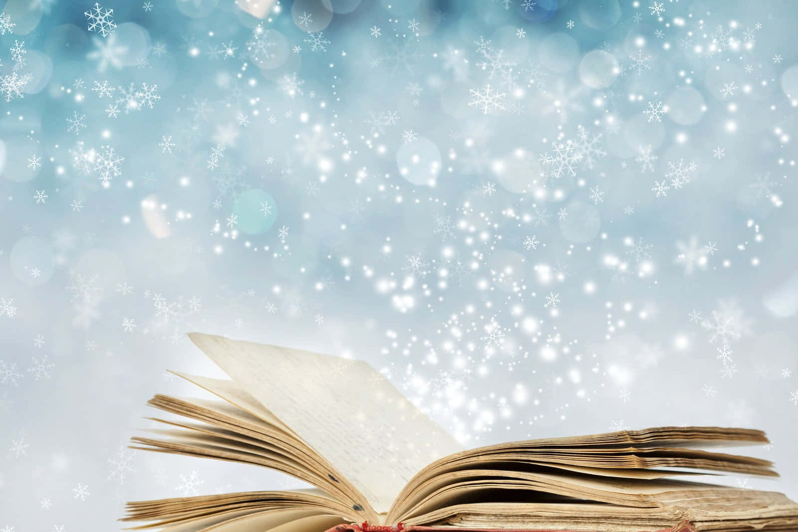 閱讀 桌布 壁紙 — 一本打開的復古書靠著閃爍的藍色背景，背景充滿飄落的雪花和散景燈光。