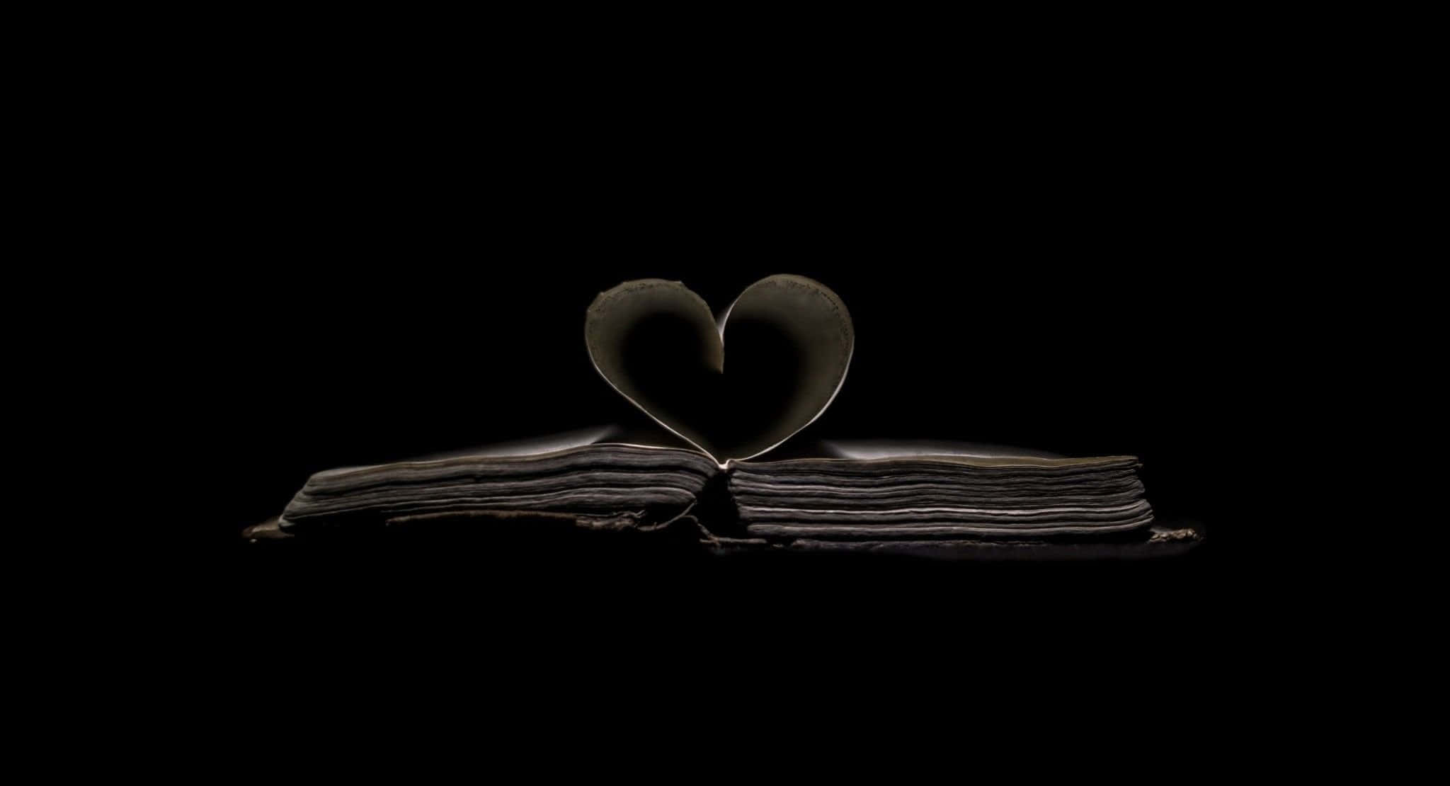 Broken Heart Black 桌布 壁紙 — 一本打開的書，書頁摺成心形，襯托在純黑背景上。