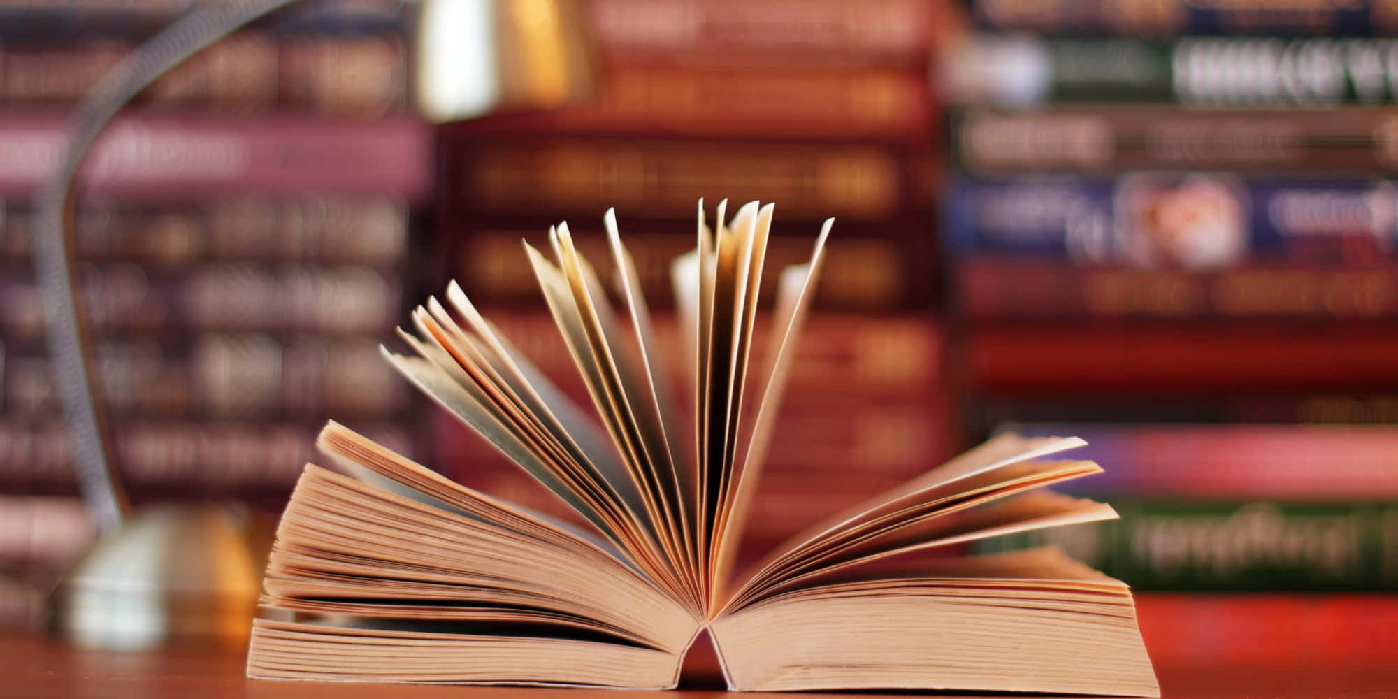 一本放在桌上的書，桌上還有其他書籍 壁紙