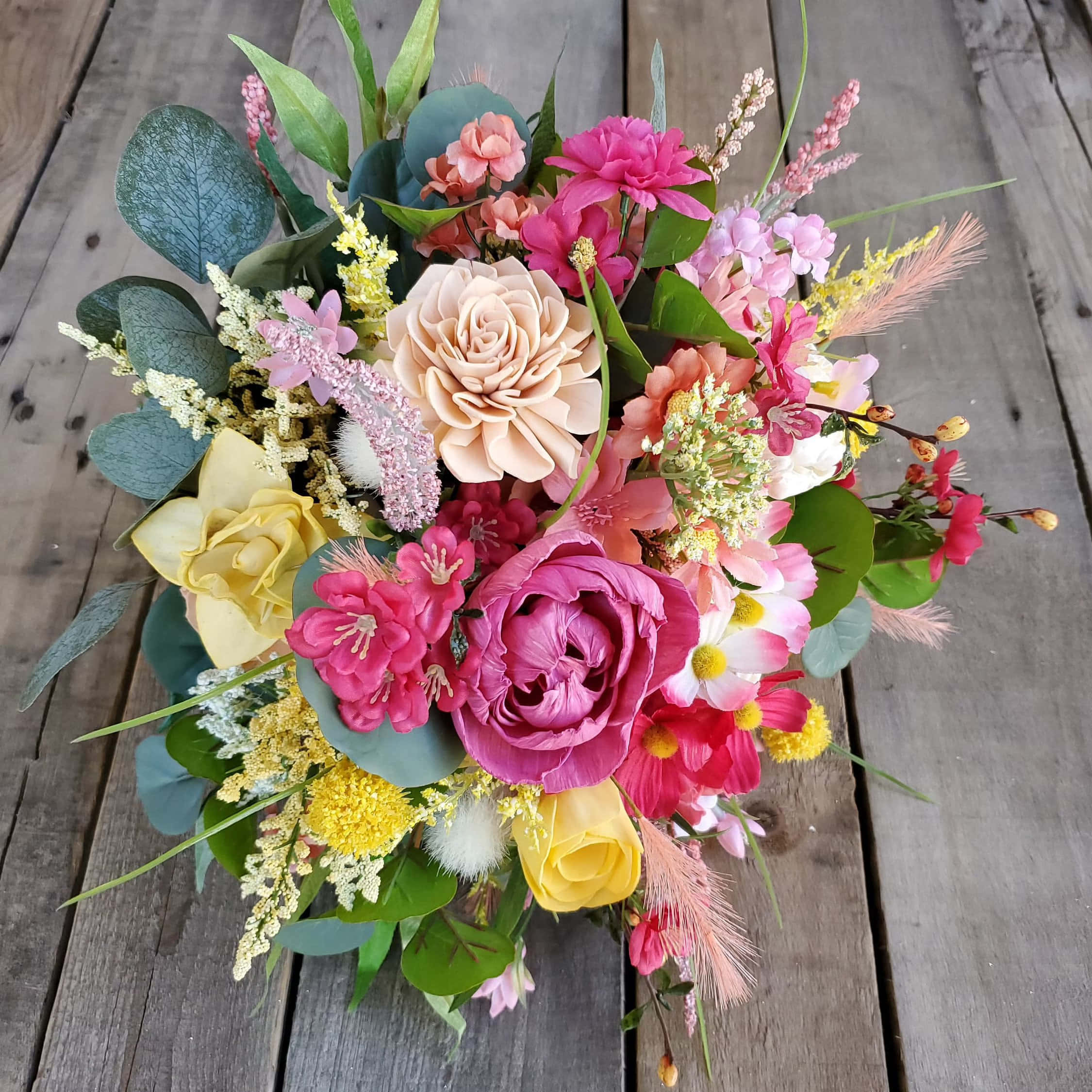 Flower Bouquet 桌布 壁紙 — 一束充滿活力的粉紅、黃色和蜜桃色花朵，搭配綠色植物，放在經風化的木質表面上。