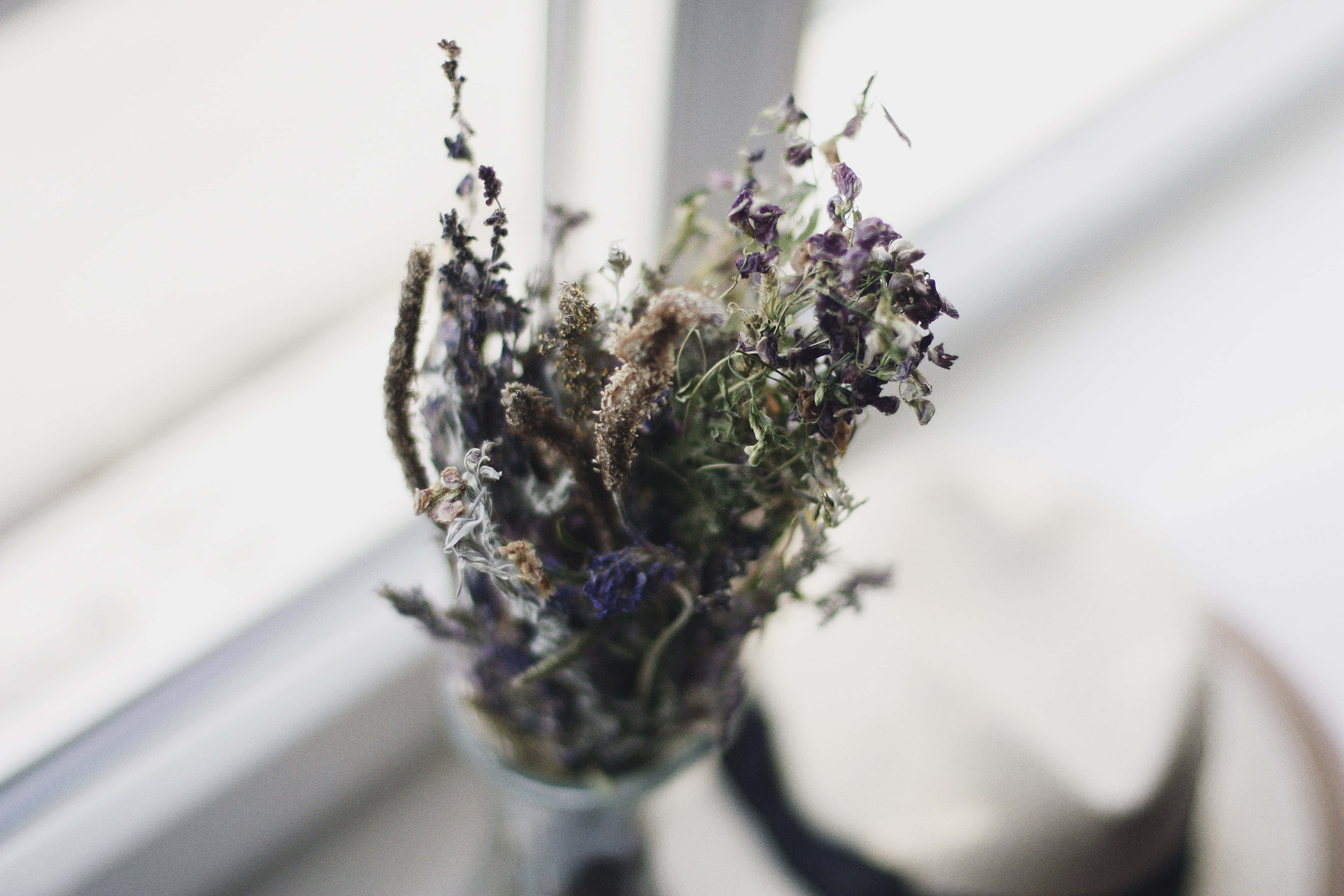 Wedding Bouquet 桌布 壁紙 — 一束精緻的乾燥紫色和綠色花朵放在玻璃花瓶裡，靠近明亮的窗戶，伴隨著柔和自然光。