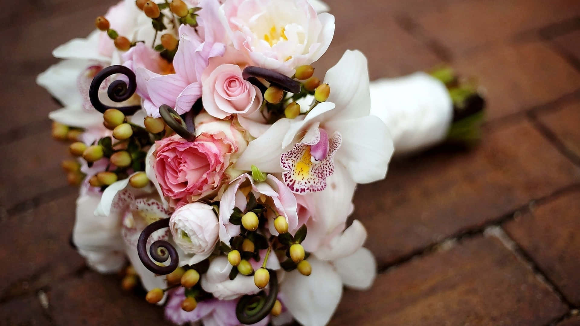 Wedding Bouquet 桌布 壁紙 — 一束精緻的新娘花束，包含粉紅玫瑰、白色蘭花和黃色漿果，放在溫暖的磚面上。