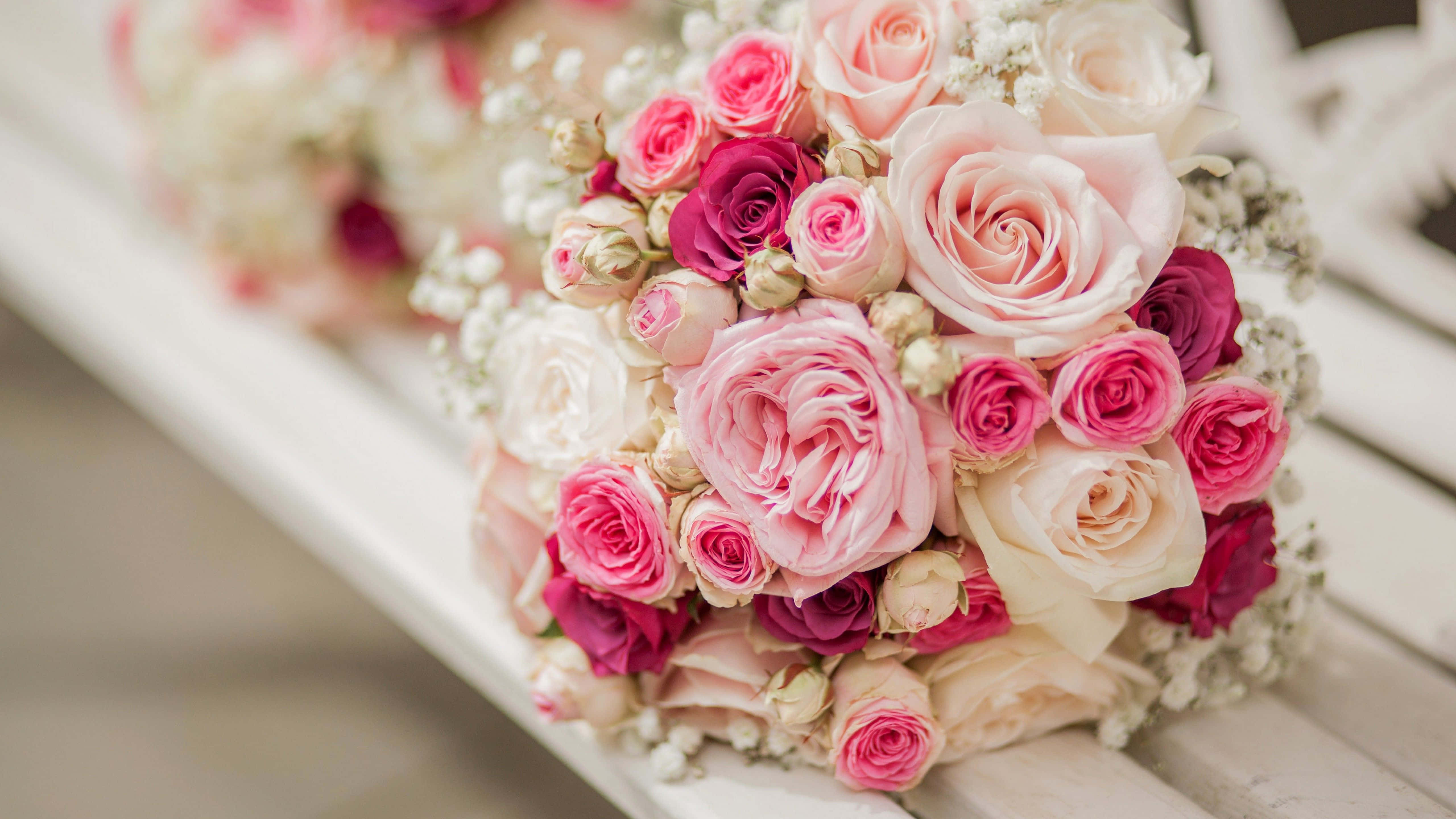 Wedding Bouquet 桌布 壁紙 — 一束茂盛的粉紅和白色玫瑰配滿天星，柔和焦點下放在白色木長椅上。