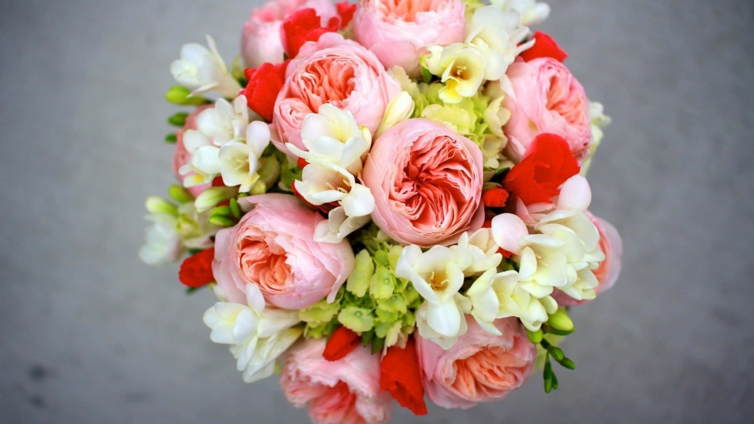 Wedding Flowers 桌布 壁紙 — 一束茂盛的粉紅蜜桃玫瑰、白色小蒼蘭和紅色花朵，以柔和浪漫的簇狀排列。