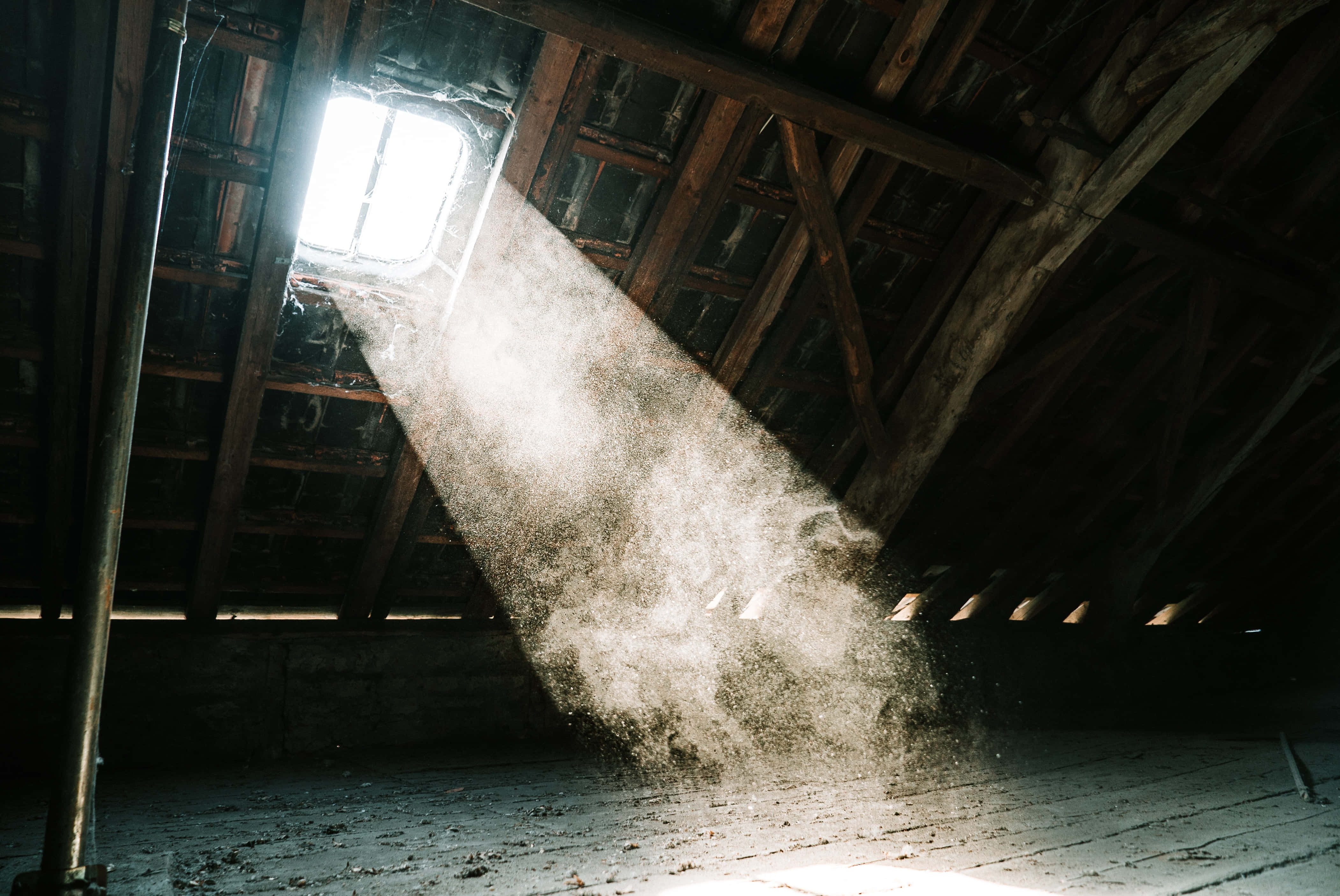 Dust 桌布 壁紙 — 一束陽光穿過天窗照進佈滿灰塵的閣樓，照亮了在深色木樑間漂浮的微粒。