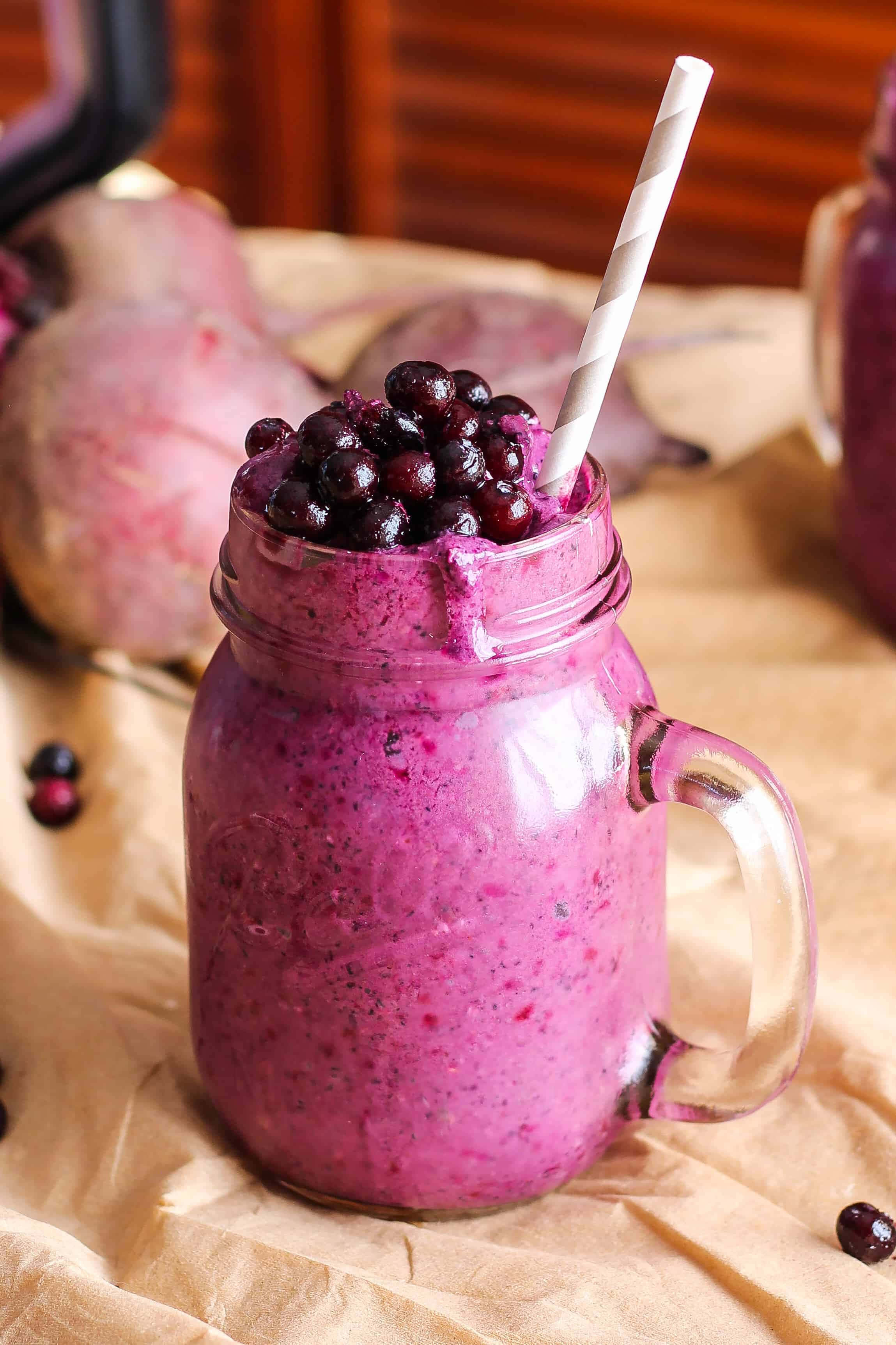 Blueberry Smoothie 桌布 壁紙 — 一杯充滿活力的紫色冰沙，上面放上新鮮藍莓，裝在玻璃梅森罐中，配上一條條紋吸管。