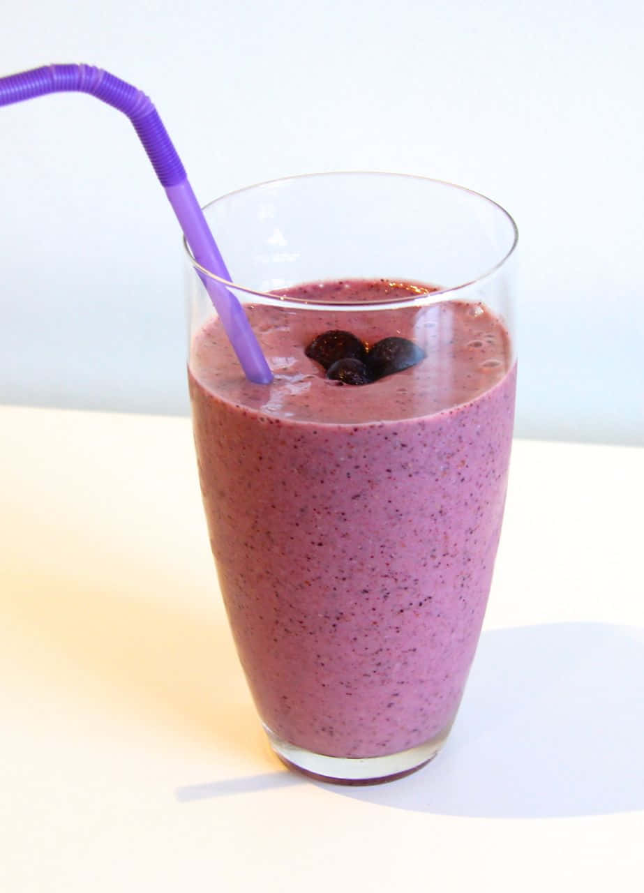 Blueberry Smoothie 桌布 壁紙 — 一杯充滿活力的紫色冰沙，盛載於透明玻璃杯中，上面綴以藍莓和紫色飲管，襯以亮白背景。
