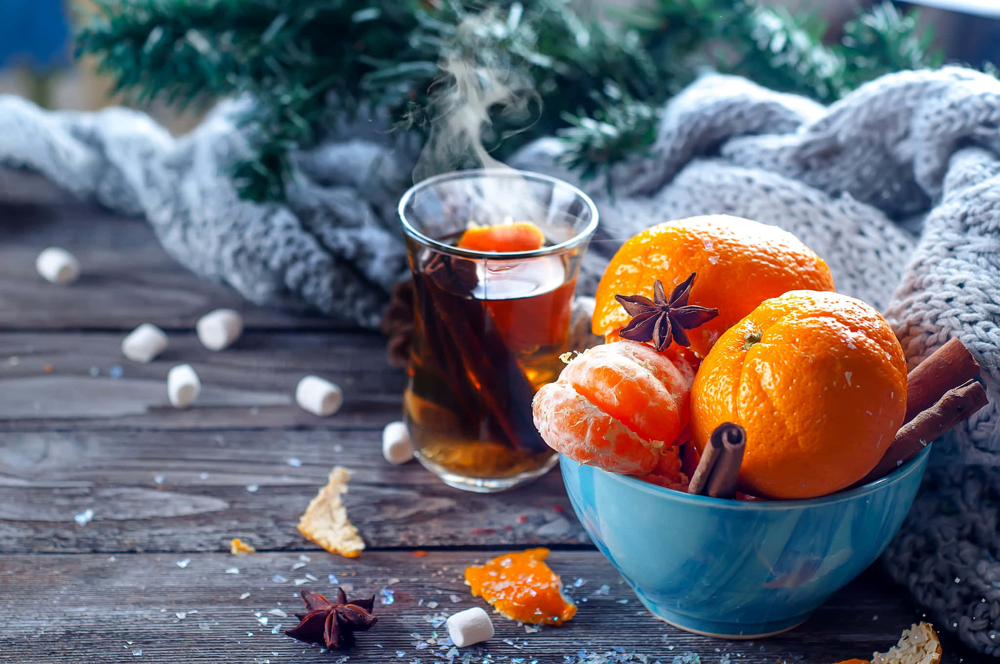 Mulled Wine 桌布 壁紙 — 一杯冒煙的香料茶，旁邊放著一碗橙子和肉桂棒，置於鄉村風木桌上。